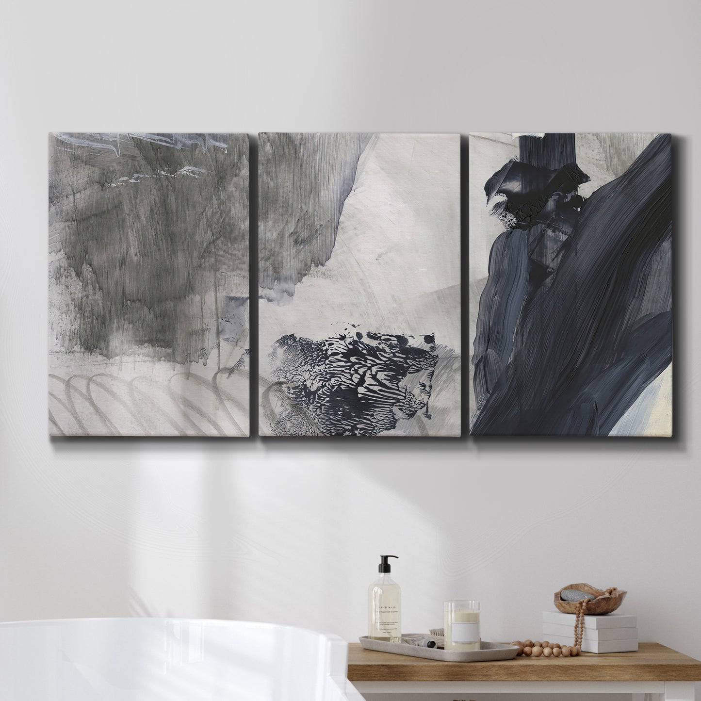 Three-panel canvas wall art featuring dark abstract atmospheric landscape, displayed in a bathroom above a bathtub.