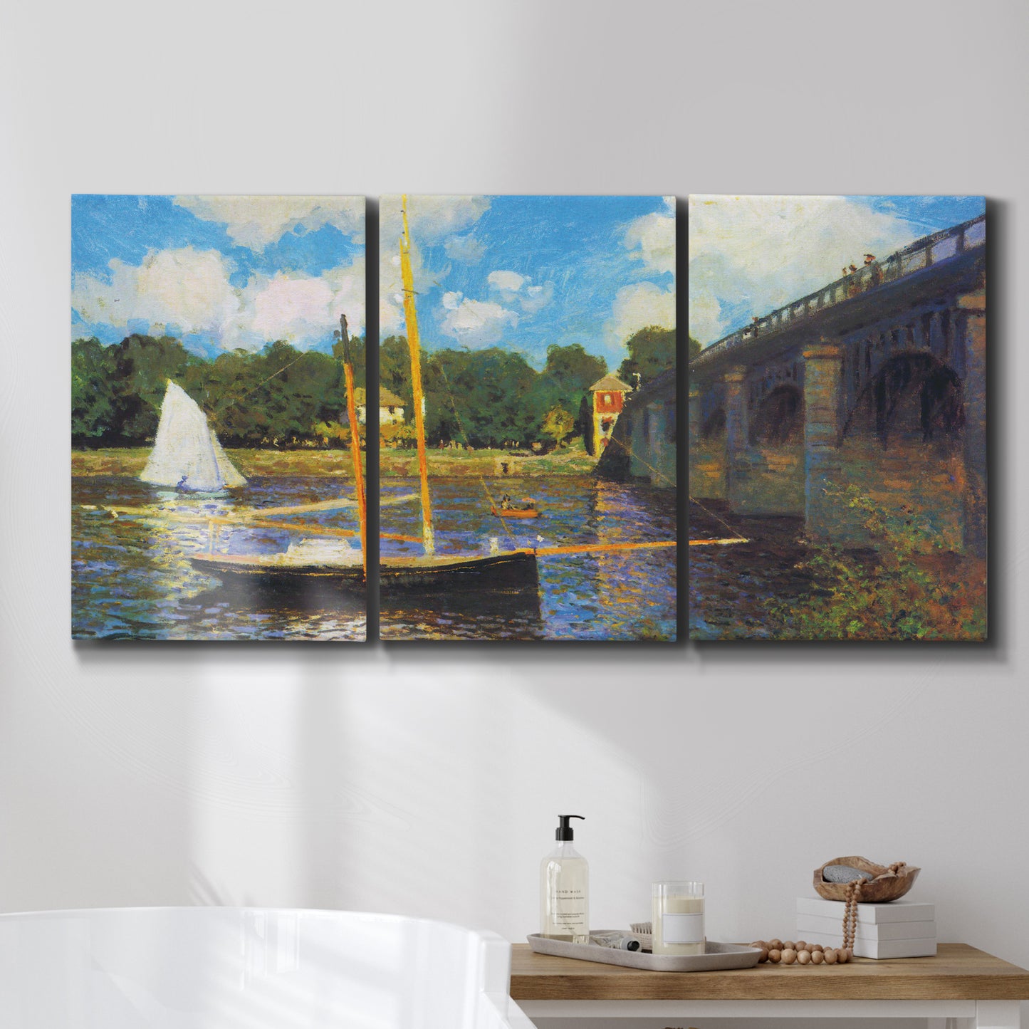 Three-panel canvas wall art featuring bridge crossing river landscape, displayed in a bathroom above a bathtub.