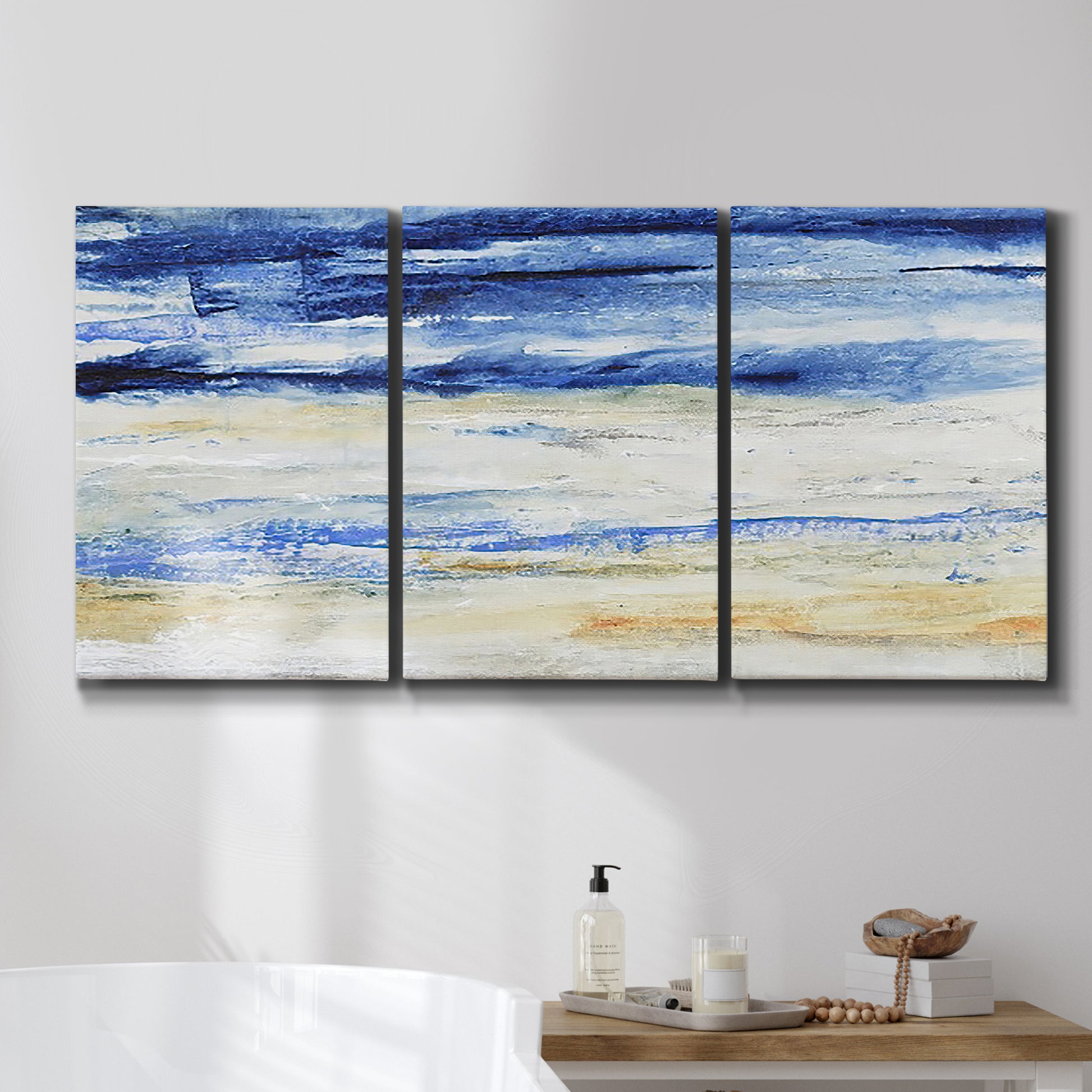 Three-panel canvas wall art featuring turbulent abstract ocean wave motion, displayed in a bathroom above a bathtub.