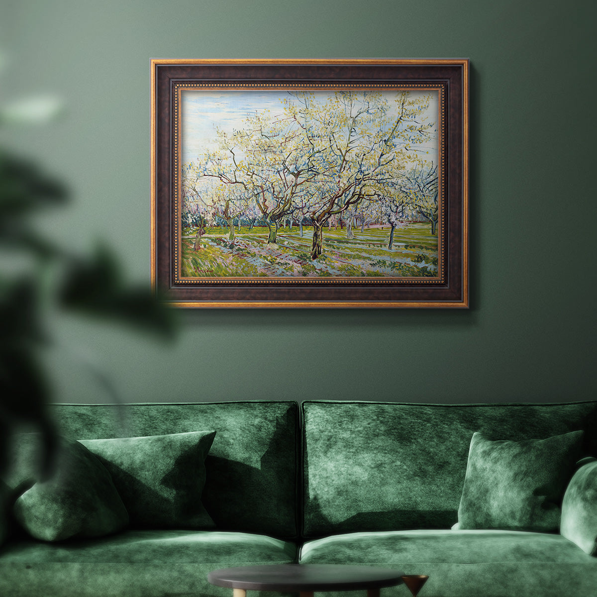 Impressionist white-blossomed orchard landscape by Vincent van Gogh in an ornate bronzed mahogany wood frame displayed in a dark-toned interior setting.