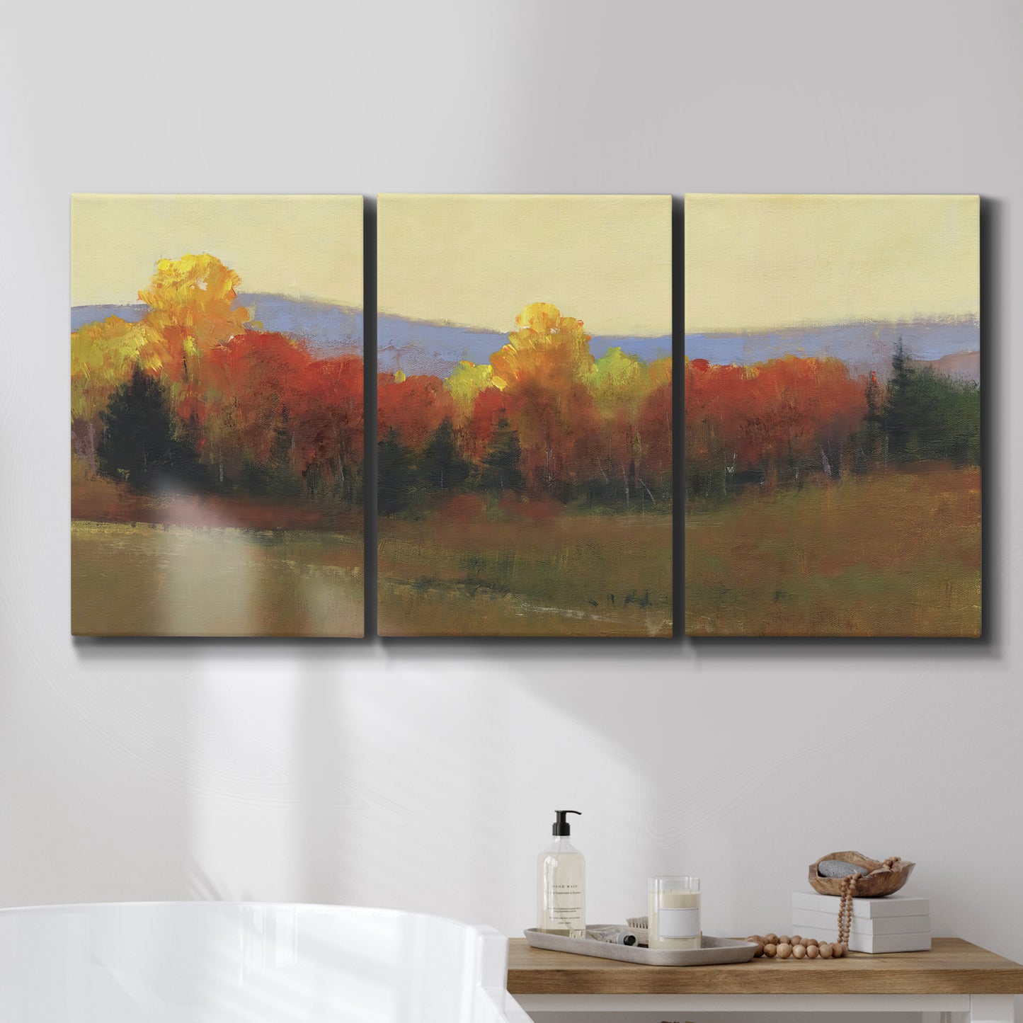 Three-panel canvas wall art featuring autumn landscape changing foliage, displayed in a bathroom above a bathtub.