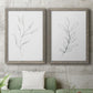 Set of two gray barnwood framed canvas prints depicting a coordinated art pair of single continuous-line leafy branches rendered as minimalist botanical line drawings above a sofa in a modern living room.