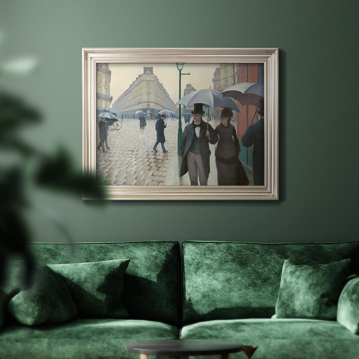 Impressionist urban street scene in the rain by Gustave Caillebotte in an ornate champagne frame displayed in a dark-toned interior setting.