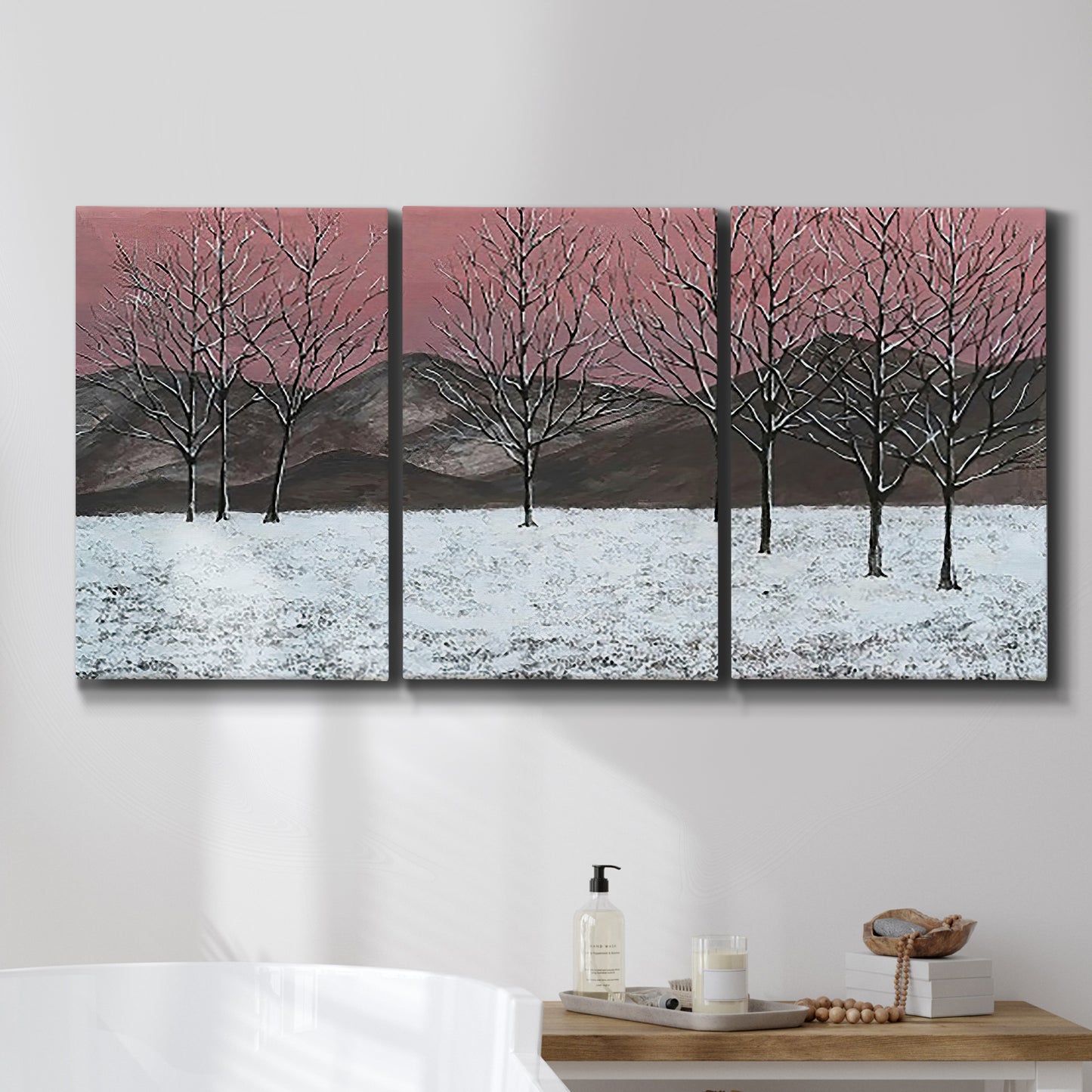 Three-panel canvas wall art featuring winter sunset snowfall landscape, displayed in a bathroom above a bathtub.