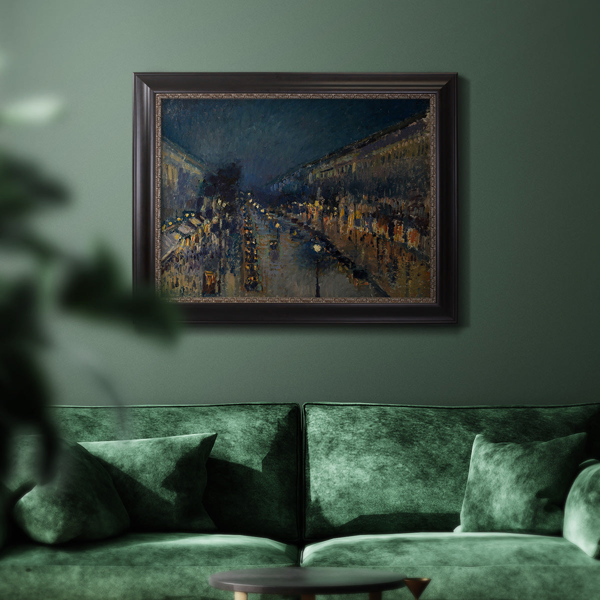Impressionist nighttime Paris street scene by Camille Pissarro in an ornate black frame with gilded inner detail displayed in a dark-toned interior setting.