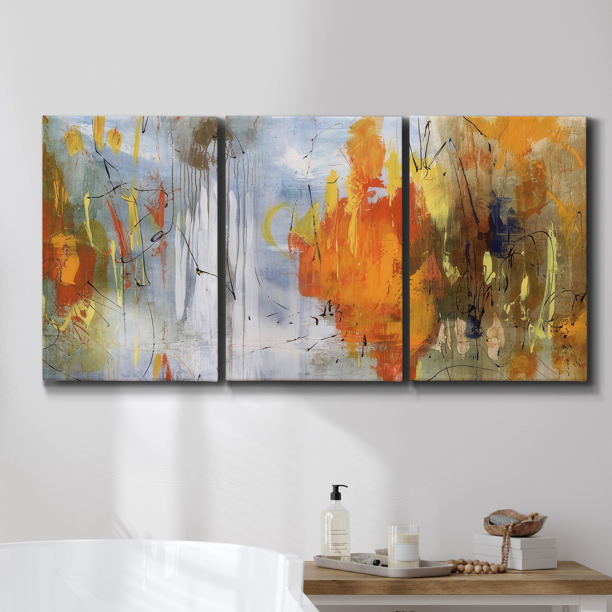 Three-panel canvas wall art featuring abstract warm sunset tones, displayed in a bathroom above a bathtub.
