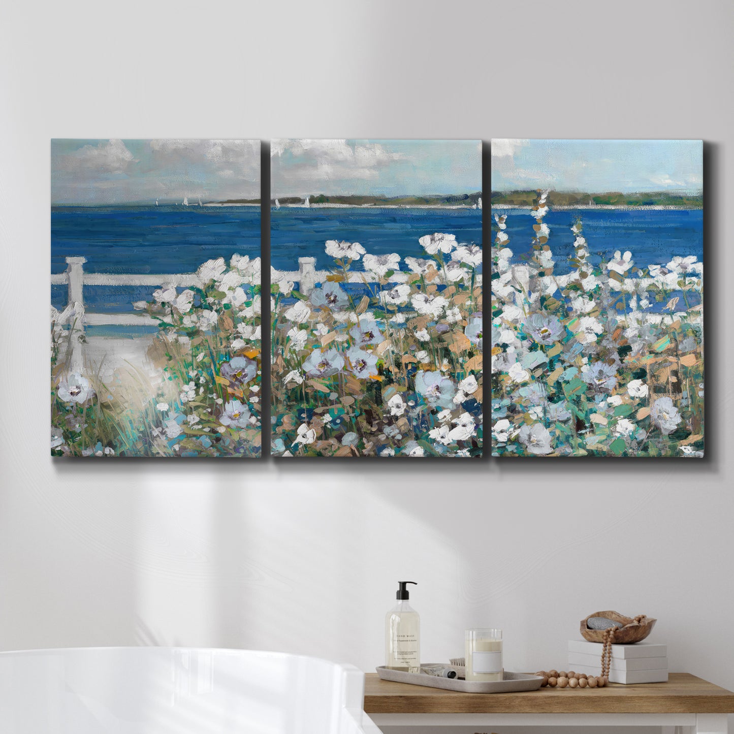 Three-panel canvas wall art featuring coastal garden overlooking bay, displayed in a bathroom above a bathtub.