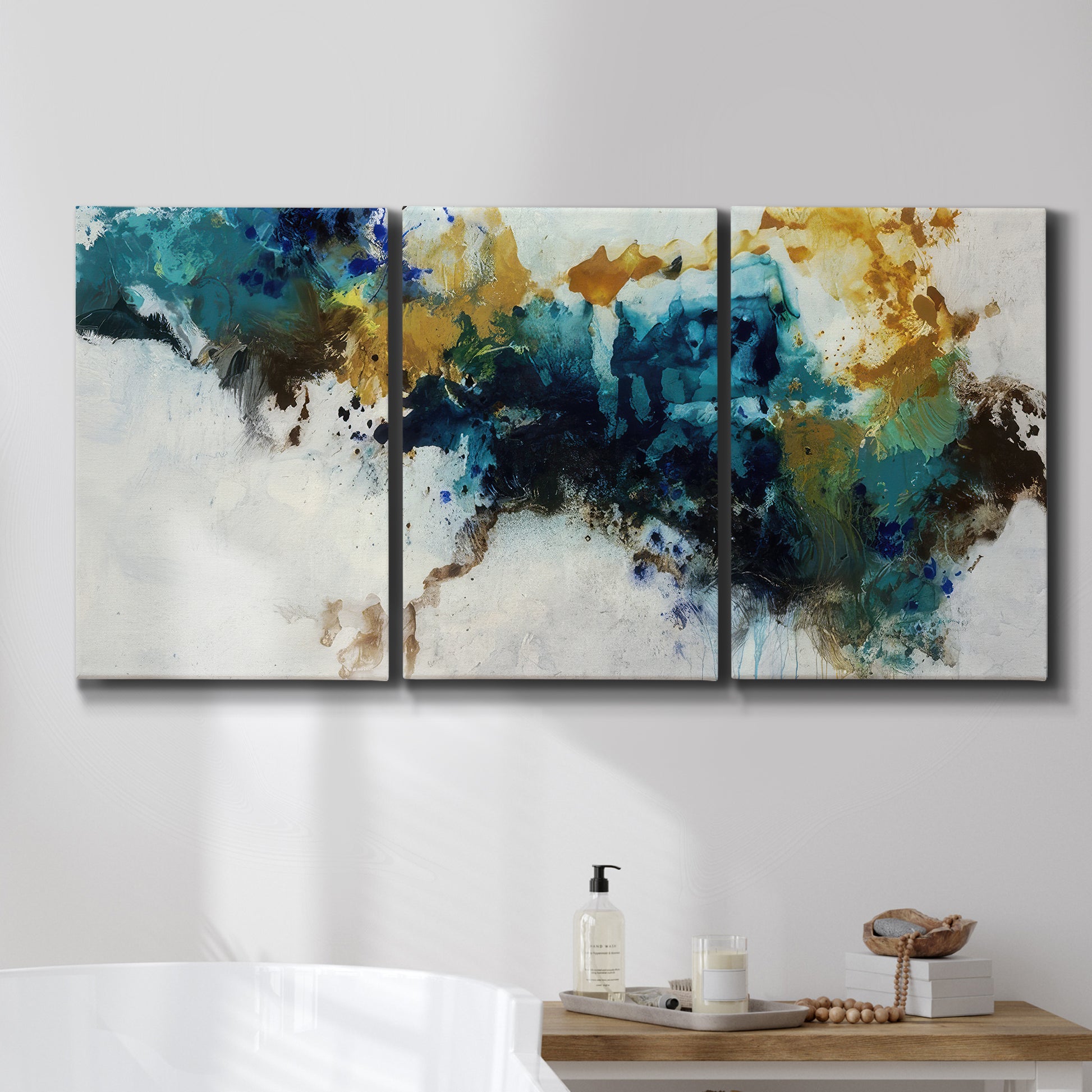 Three-panel canvas wall art featuring teal abstract paint splatter, displayed in a bathroom above a bathtub.