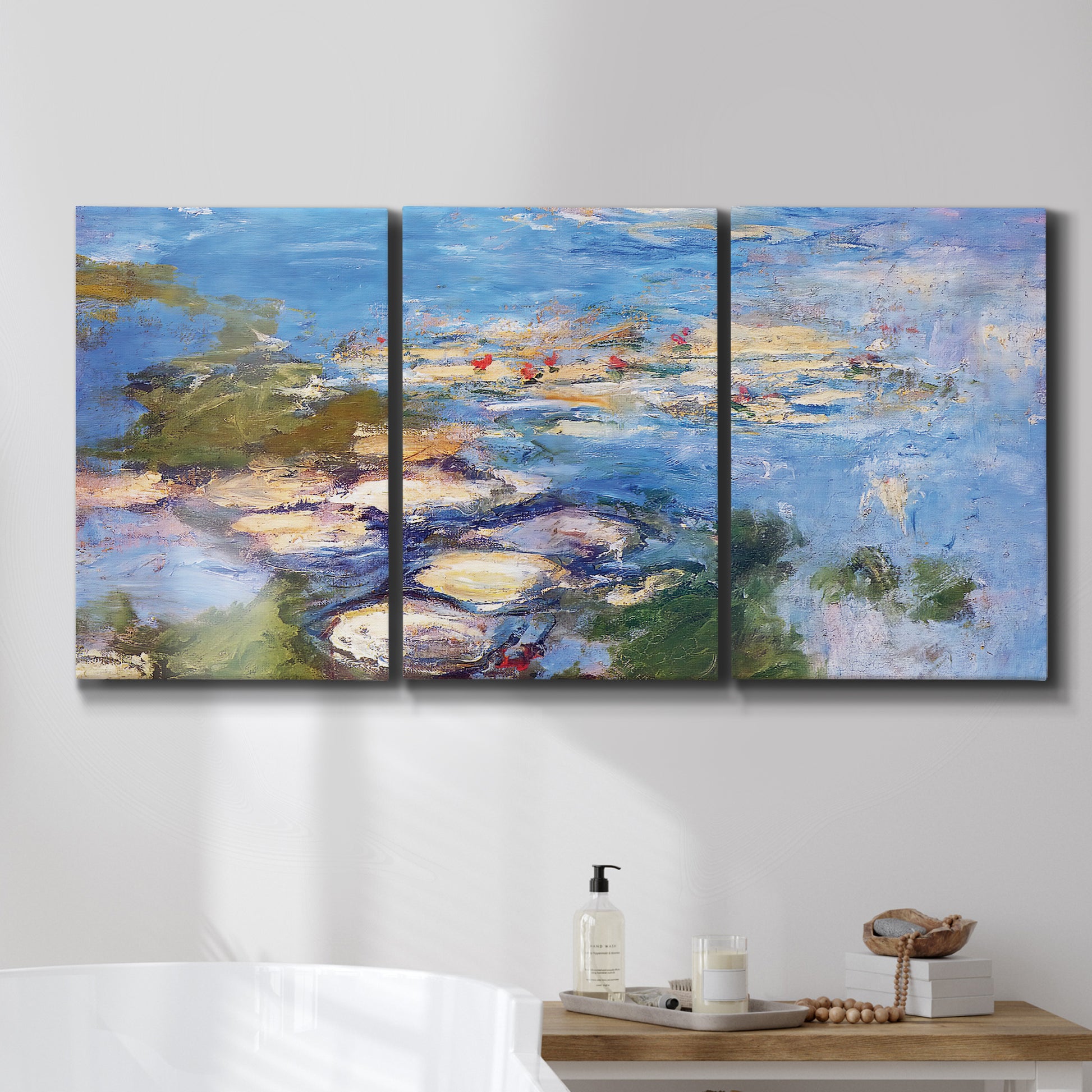 Three-panel canvas wall art featuring water lilies in blue and gold, displayed in a bathroom above a bathtub.