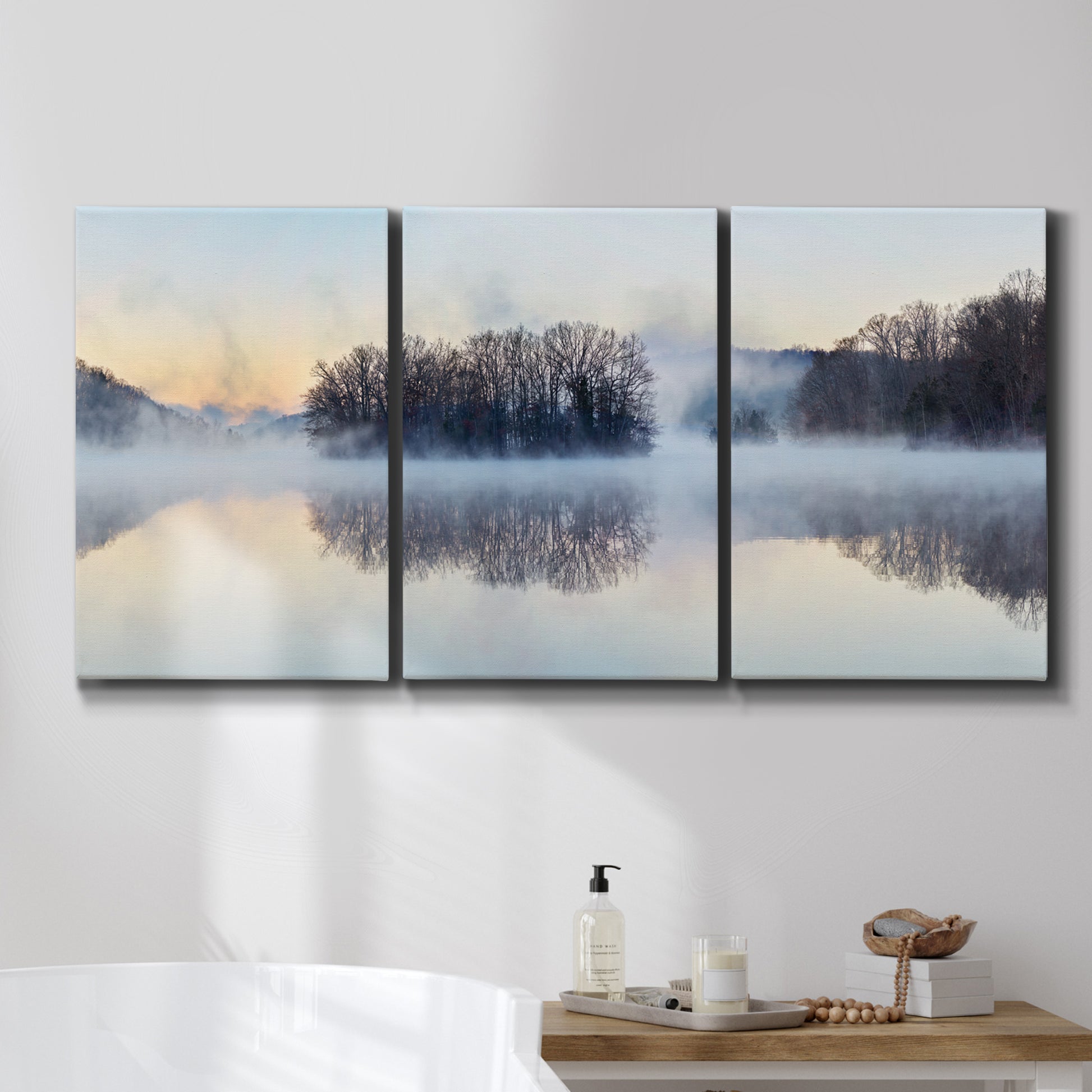Three-panel canvas wall art featuring misty water landscape photograph, displayed in a bathroom above a bathtub.