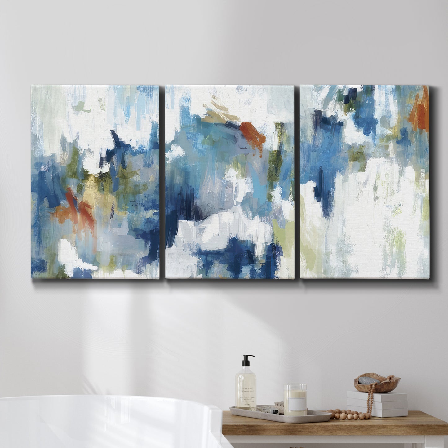 Three-panel canvas wall art featuring flowing abstract color movement, displayed in a bathroom above a bathtub.