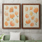 Set of two maple barnwood framed canvas prints depicting a coordinated art pair of loose peach-orange tulip-like blossoms rendered as airy watercolor floral paintings above a sofa in a modern living room.