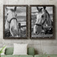 Set of two black barnwood framed canvas prints depicting a coordinated art pair of black-and-white close-up portraits of horses at fences rendered as modern equestrian photography above a sofa in a modern living room.