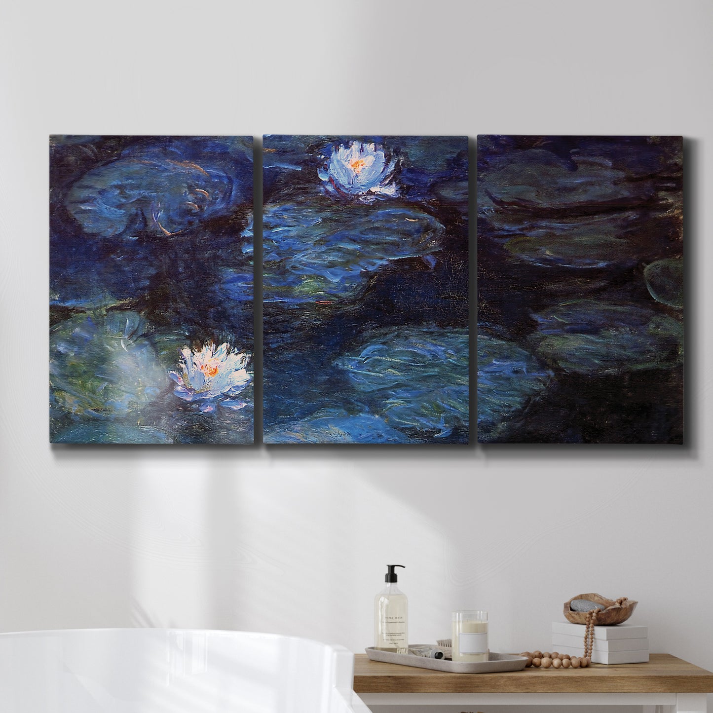 Three-panel canvas wall art featuring deep blue water lily reflections, displayed in a bathroom above a bathtub.