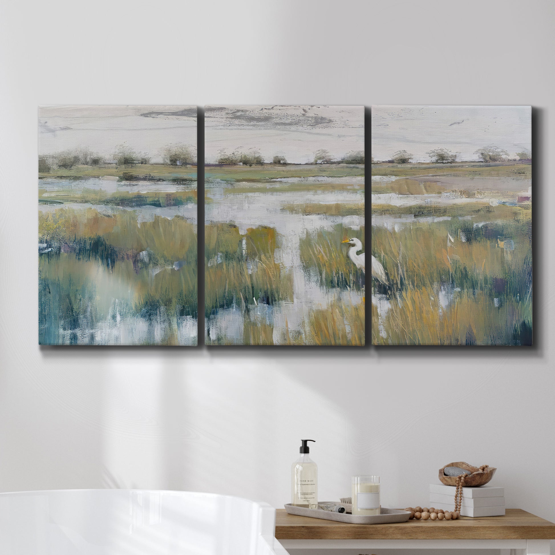 Three-panel canvas wall art featuring pastoral marshland landscape, displayed in a bathroom above a bathtub.
