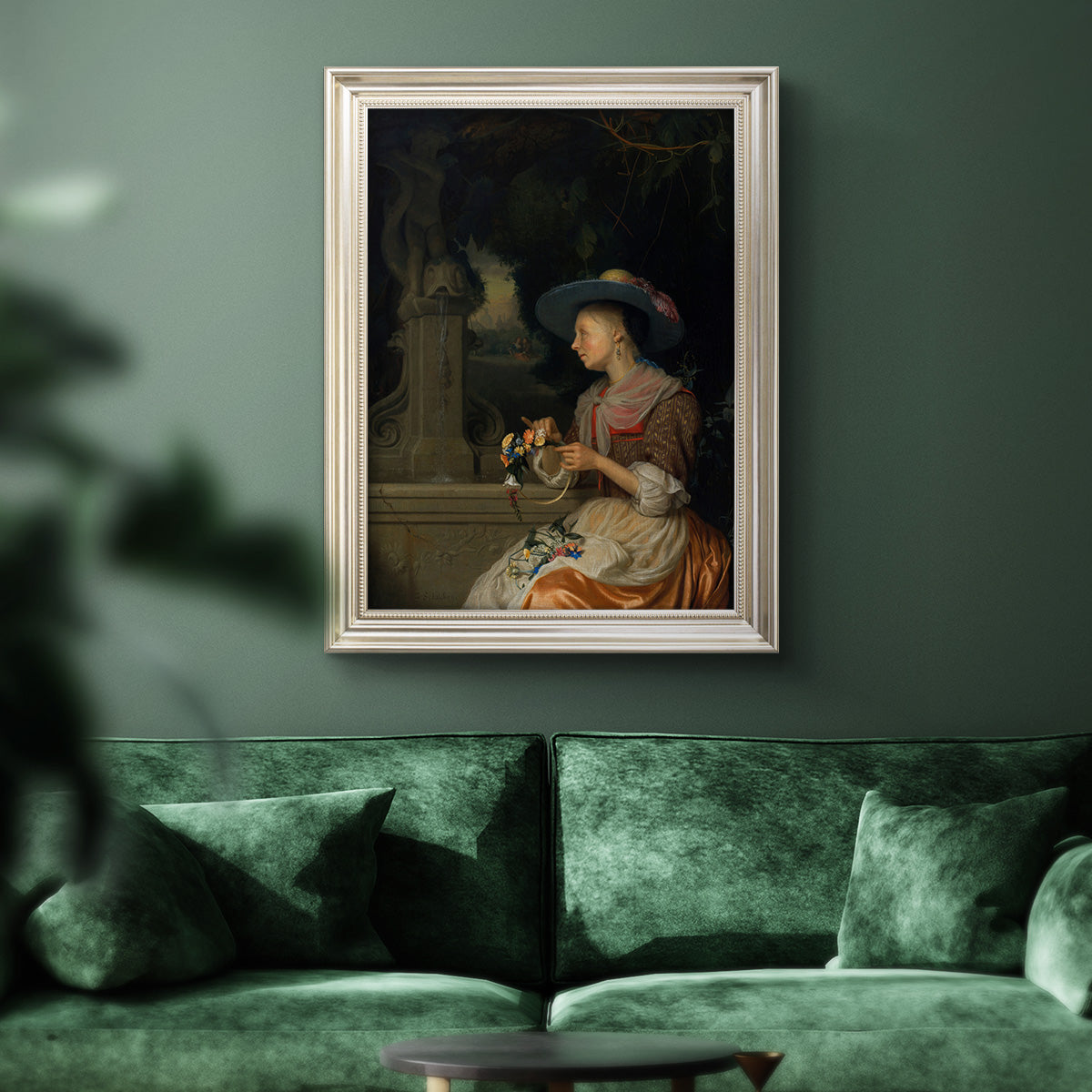 Classical interior scene of a woman weaving flowers by Godfried Schalcken in an ornate champagne frame displayed in a dark-toned interior setting.