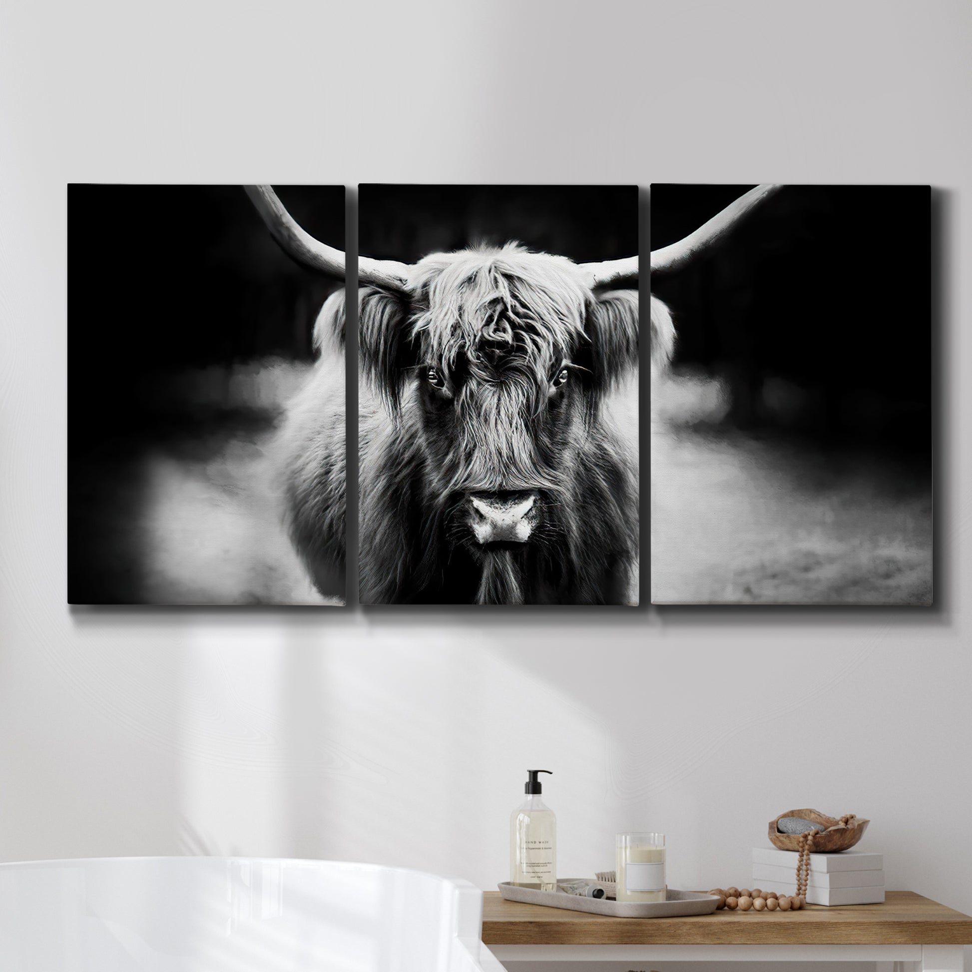 Three-panel canvas wall art featuring black and white cattle portrait, displayed in a bathroom above a bathtub.