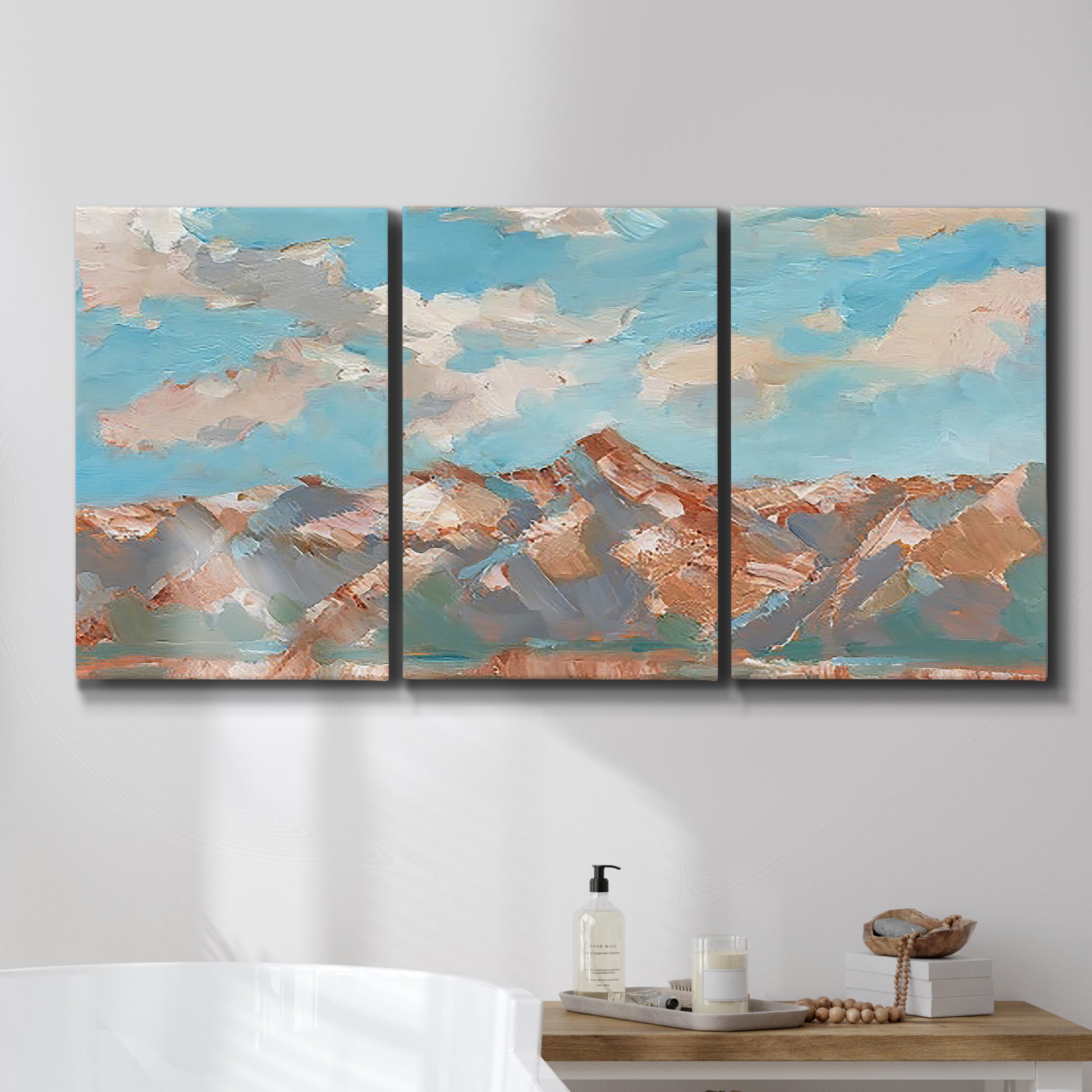 Three-panel canvas wall art featuring soft pastel western hills landscape, displayed in a bathroom above a bathtub.