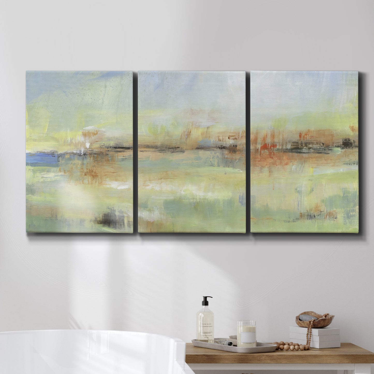 Three-panel canvas wall art featuring layered abstract transitional textures, displayed in a bathroom above a bathtub.