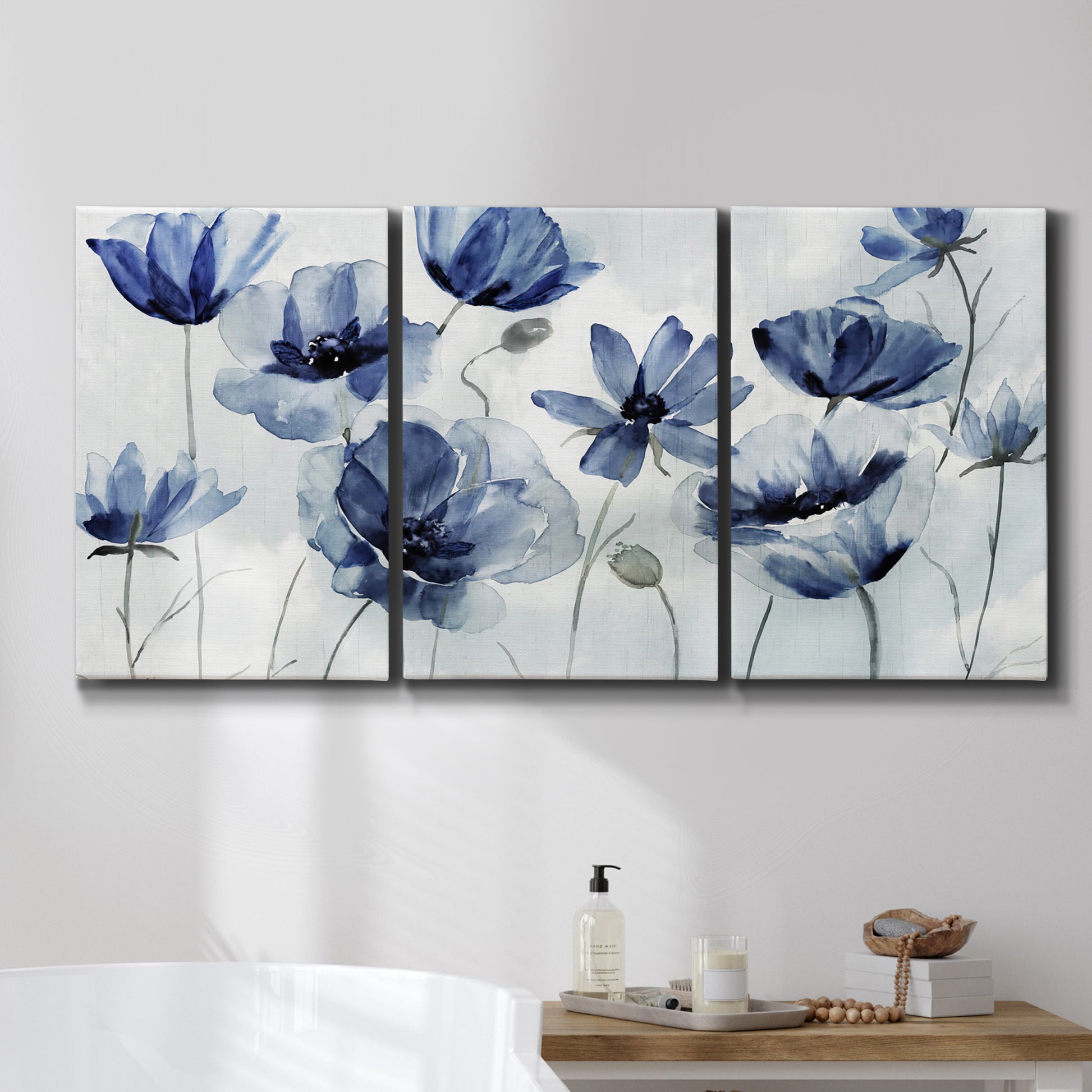 Three-panel canvas wall art featuring indigo floral blossoms awakening, displayed in a bathroom above a bathtub.