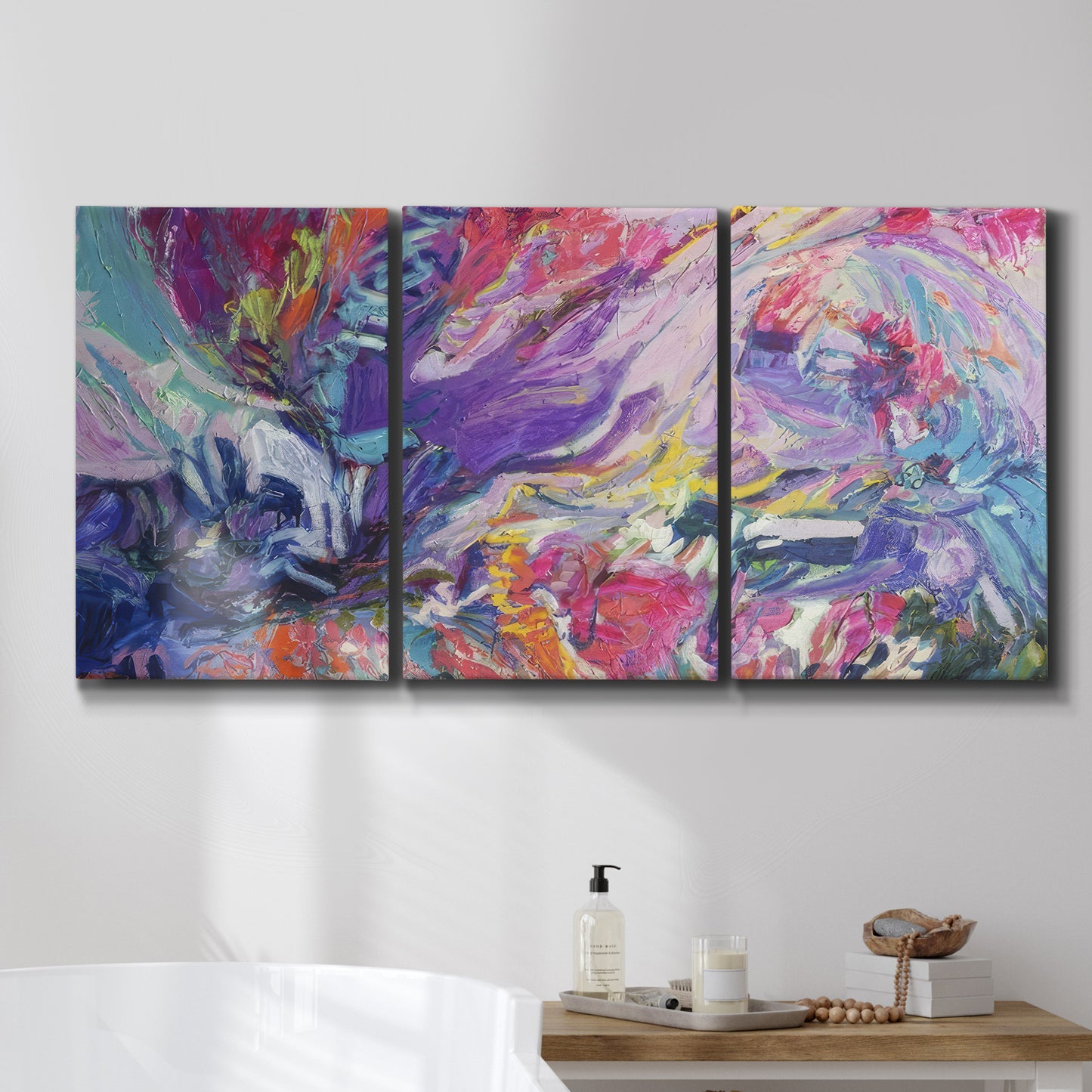 Three-panel canvas wall art featuring expressive abstract with layered color, displayed in a bathroom above a bathtub.