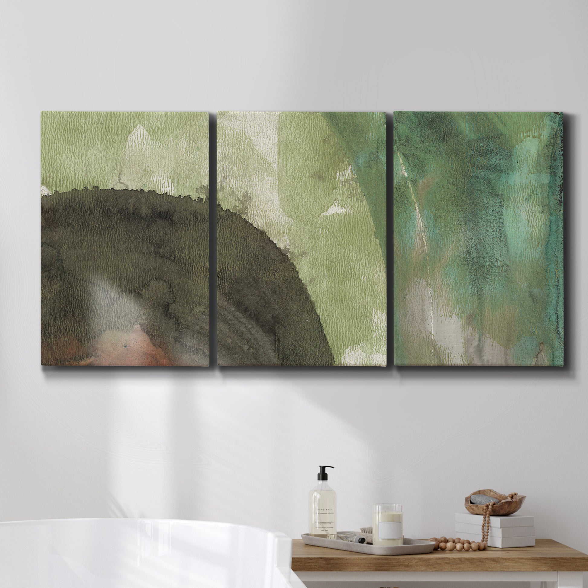 Three-panel canvas wall art featuring layered green abstract composition, displayed in a bathroom above a bathtub.