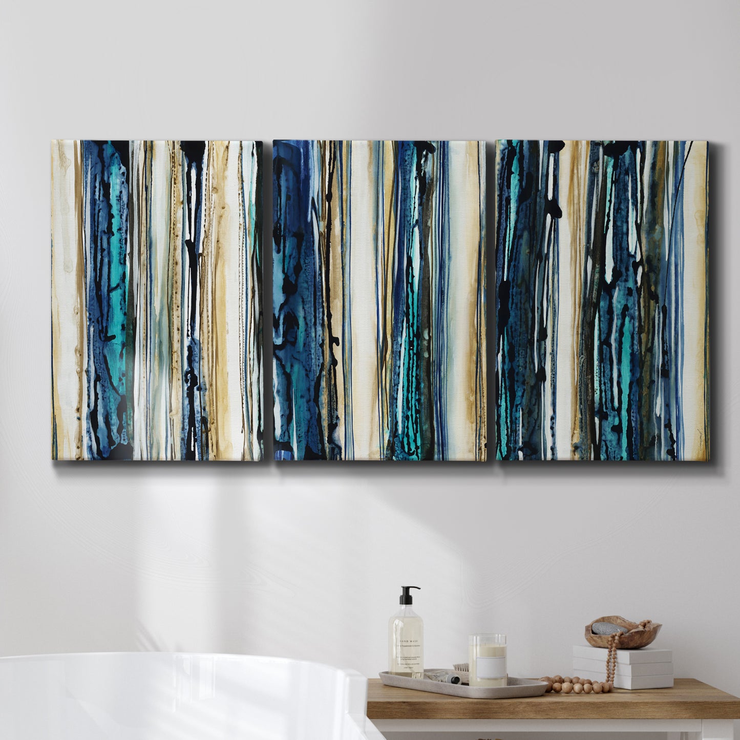 Three-panel canvas wall art featuring vertical blue abstract streaks, displayed in a bathroom above a bathtub.