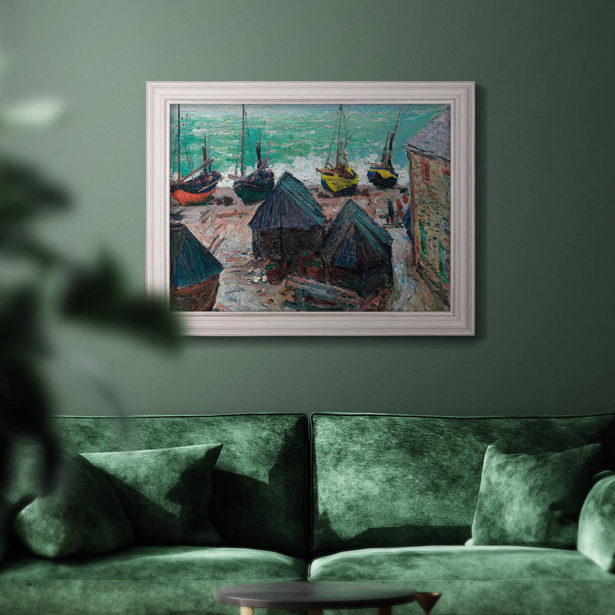 Impressionist coastal beach scene with boats by Claude Monet in an ornate weathered white frame displayed in a dark-toned interior setting.