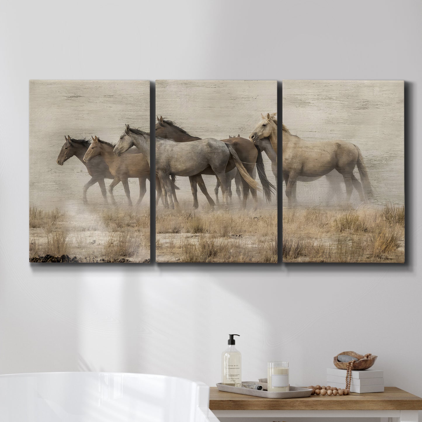 Three-panel canvas wall art featuring wild horses roaming open terrain, displayed in a bathroom above a bathtub.