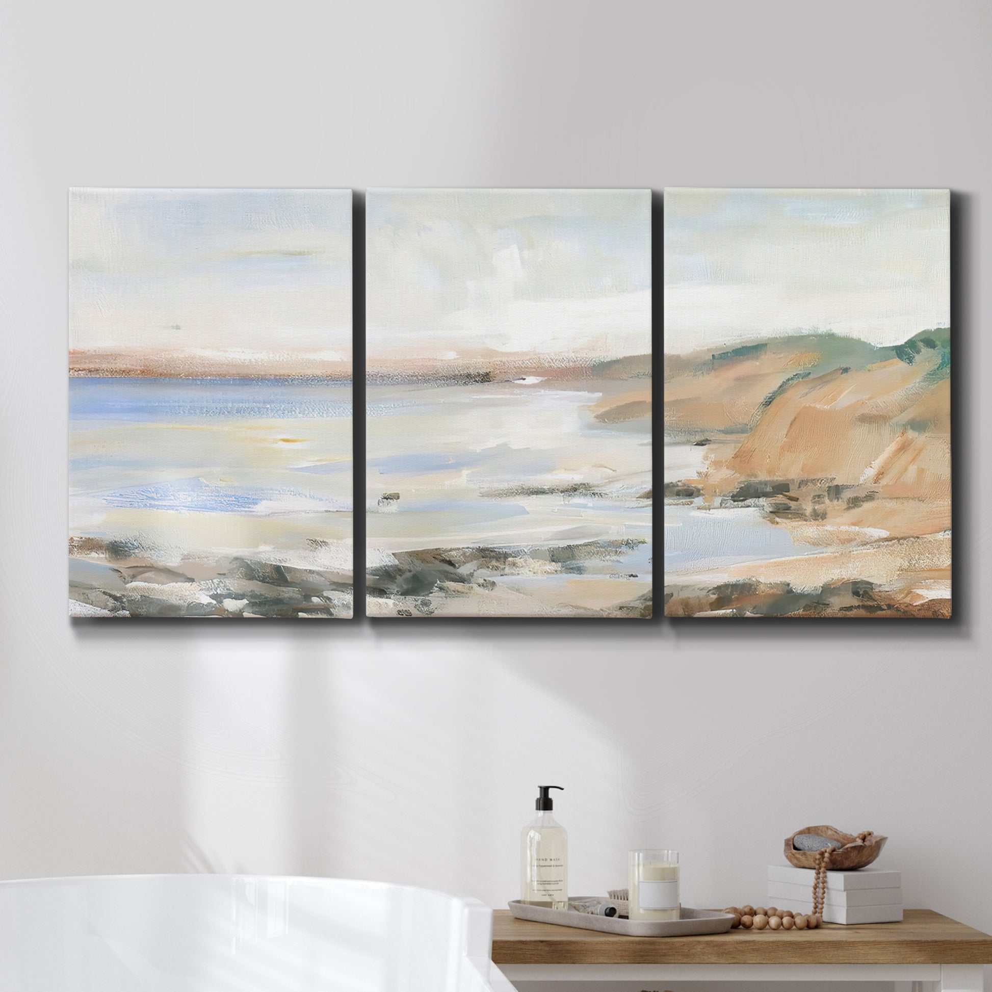 Three-panel canvas wall art featuring coastal shoreline landscape study, displayed in a bathroom above a bathtub.