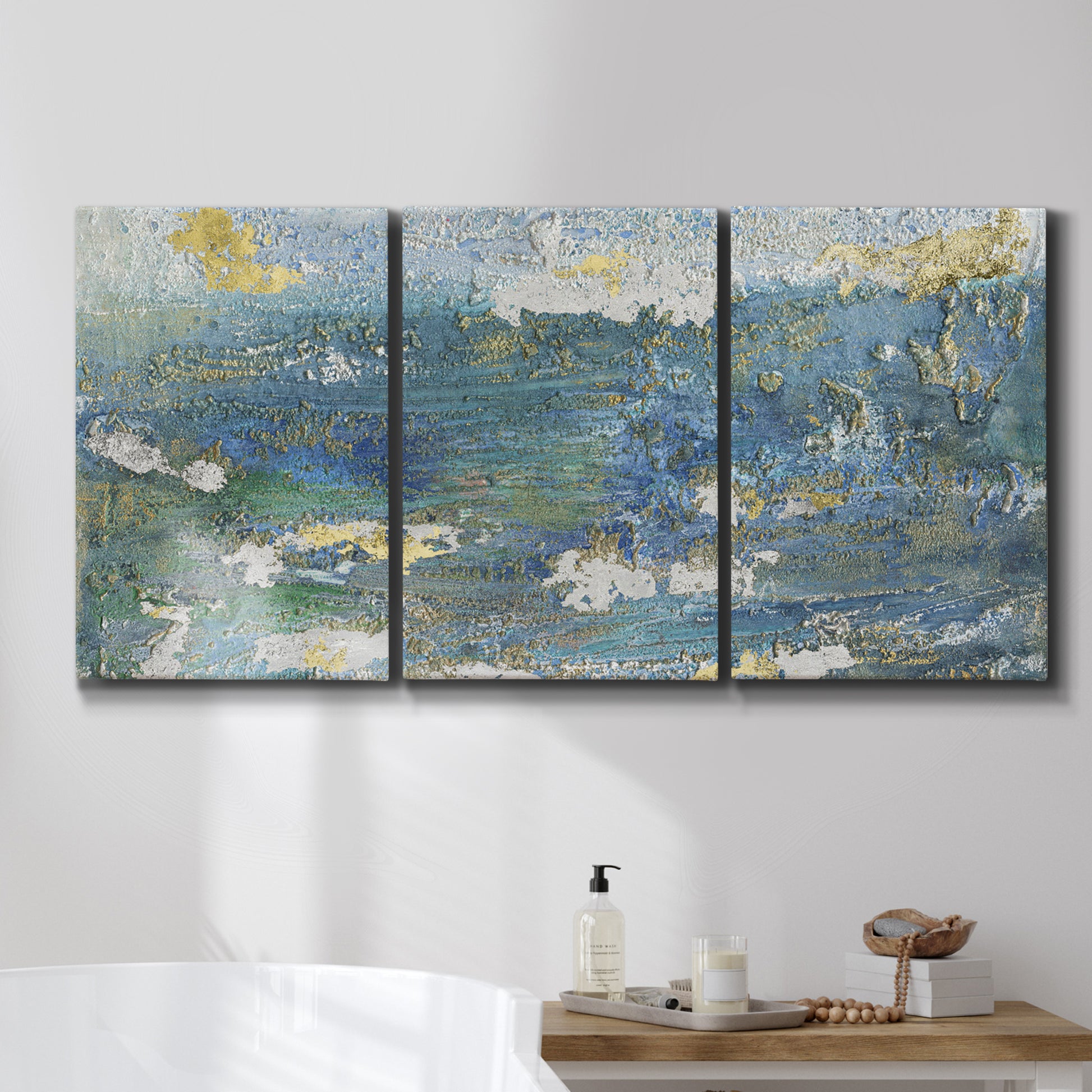 Three-panel canvas wall art featuring sparkling abstract sea surface, displayed in a bathroom above a bathtub.
