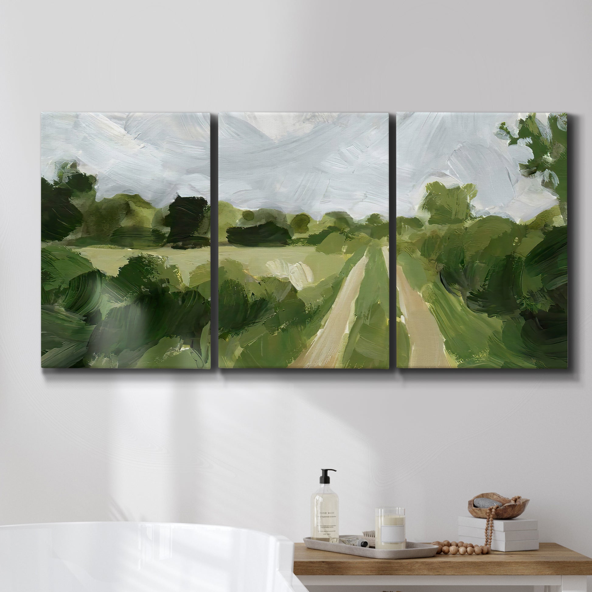 Three-panel canvas wall art featuring meadow trail through open grassland, displayed in a bathroom above a bathtub.