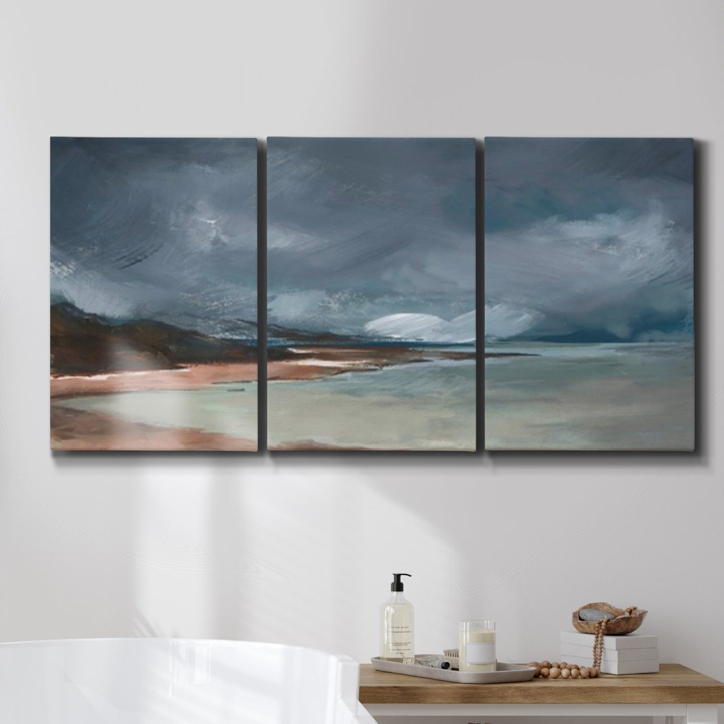 Three-panel canvas wall art featuring stormy sea glass toned coastline, displayed in a bathroom above a bathtub.