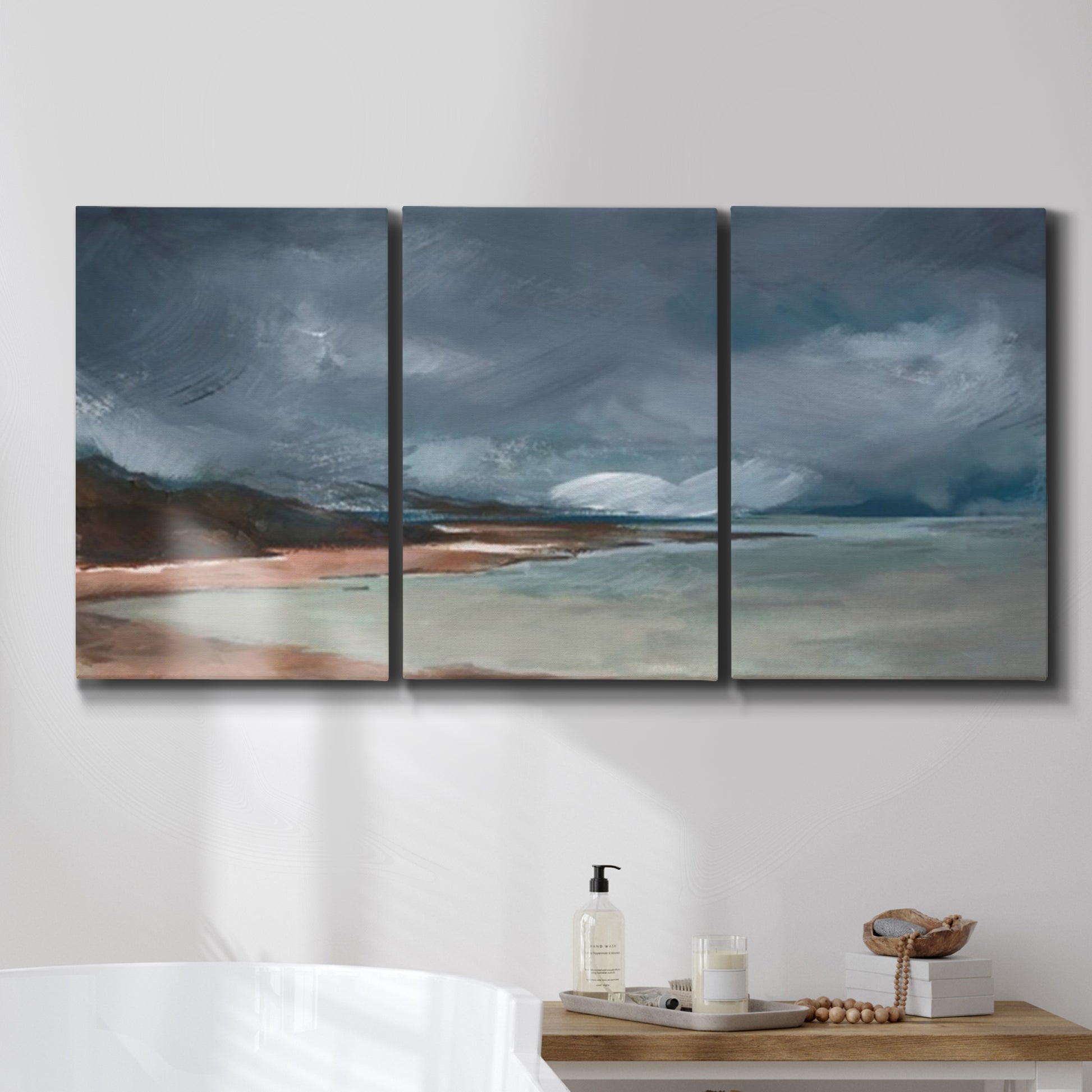 Three-panel canvas wall art featuring stormy sea glass toned coastline, displayed in a bathroom above a bathtub.