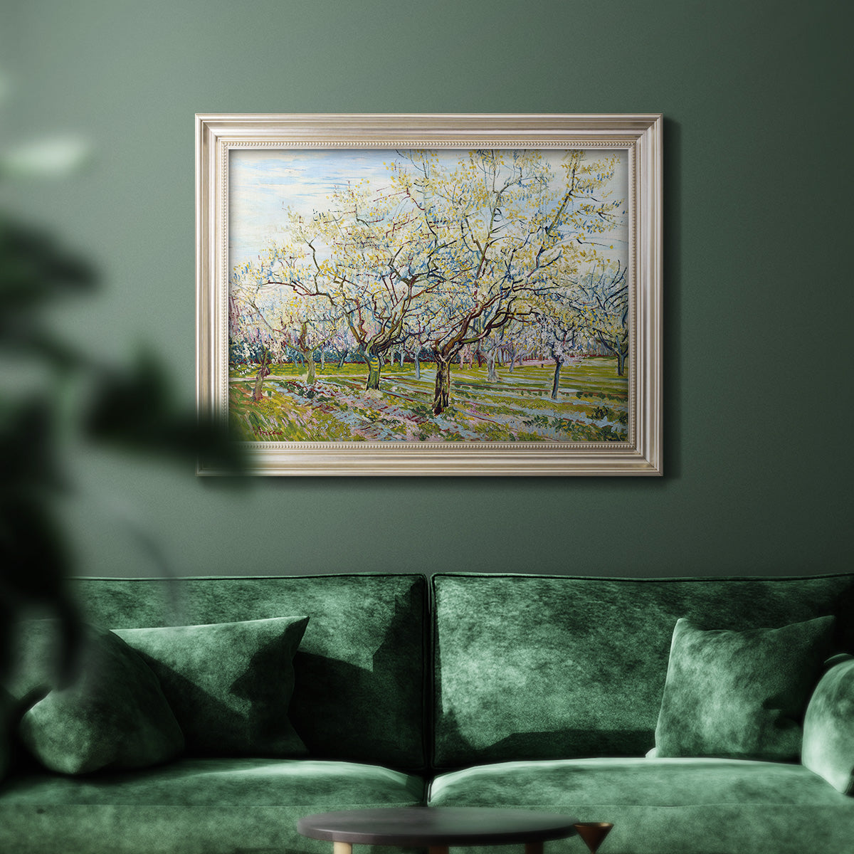 Impressionist white-blossomed orchard landscape by Vincent van Gogh in an ornate champagne frame displayed in a dark-toned interior setting.