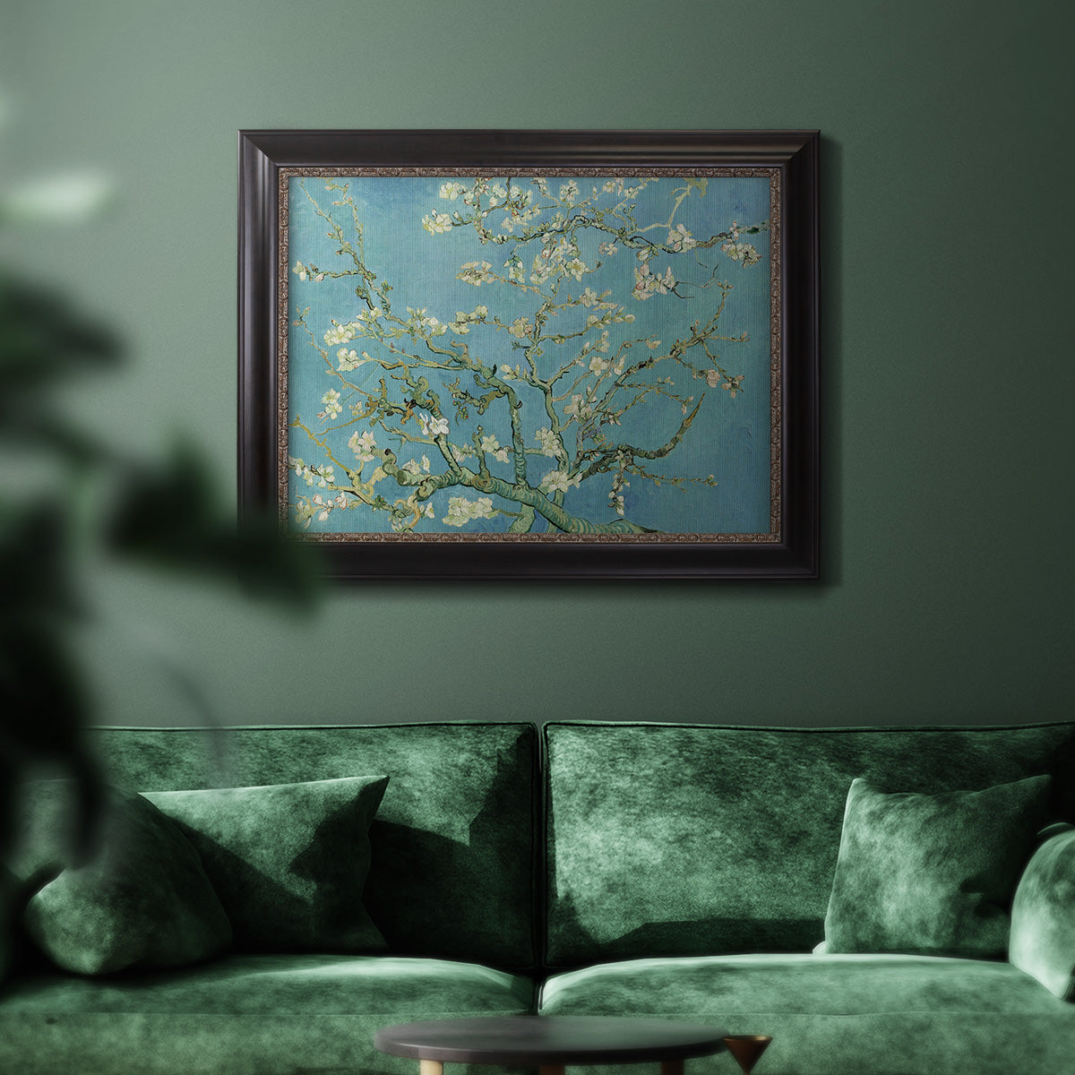 Impressionist flowering almond branch painting by Vincent van Gogh in an ornate black frame with gilded inner detail displayed in a dark-toned interior setting.
