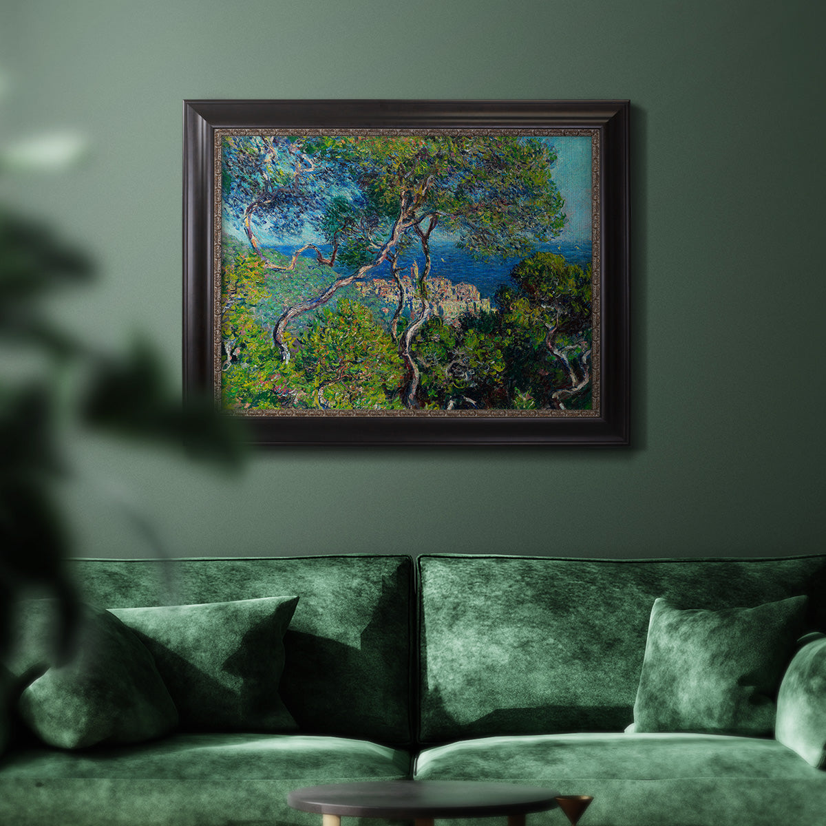 Impressionist Mediterranean coastal landscape by Claude Monet in an ornate black frame with gilded inner detail displayed in a dark-toned interior setting.