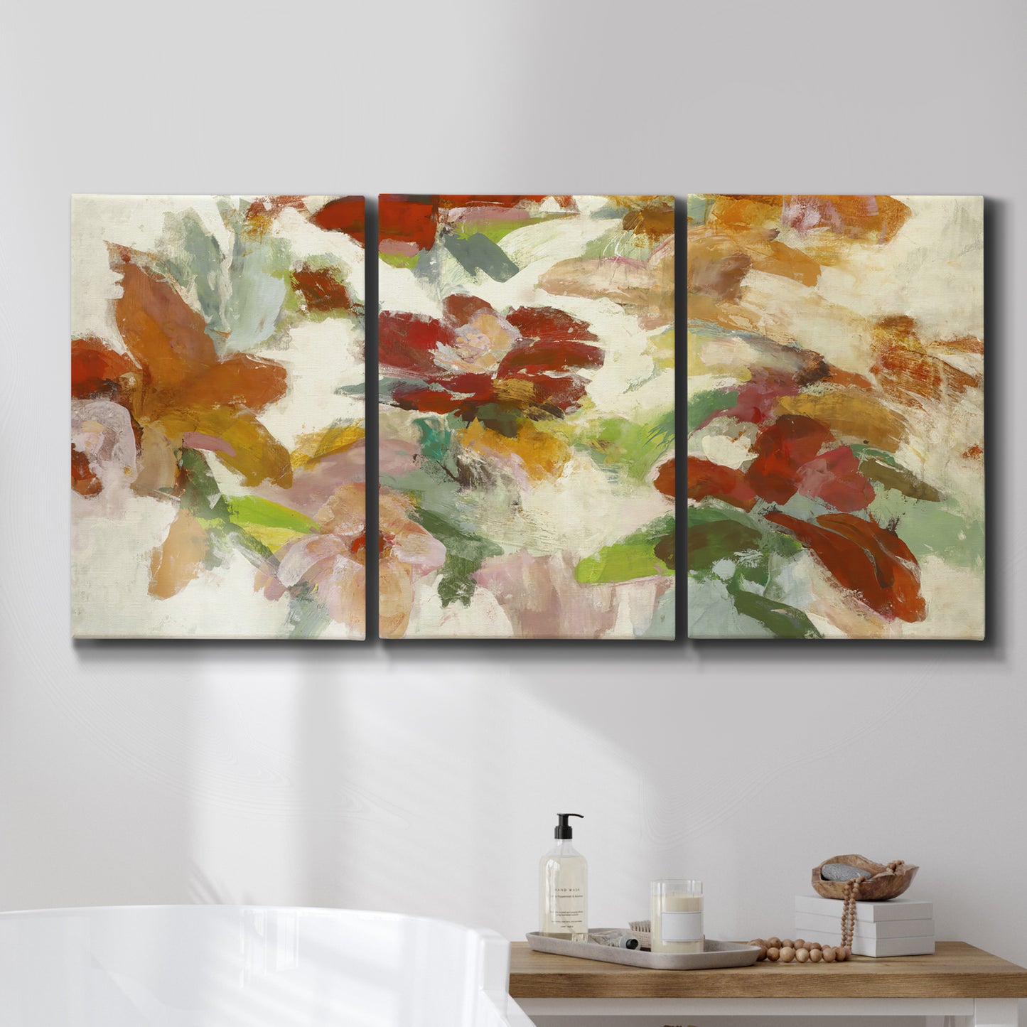 Three-panel canvas wall art featuring layered floral botanical impressions, displayed in a bathroom above a bathtub.