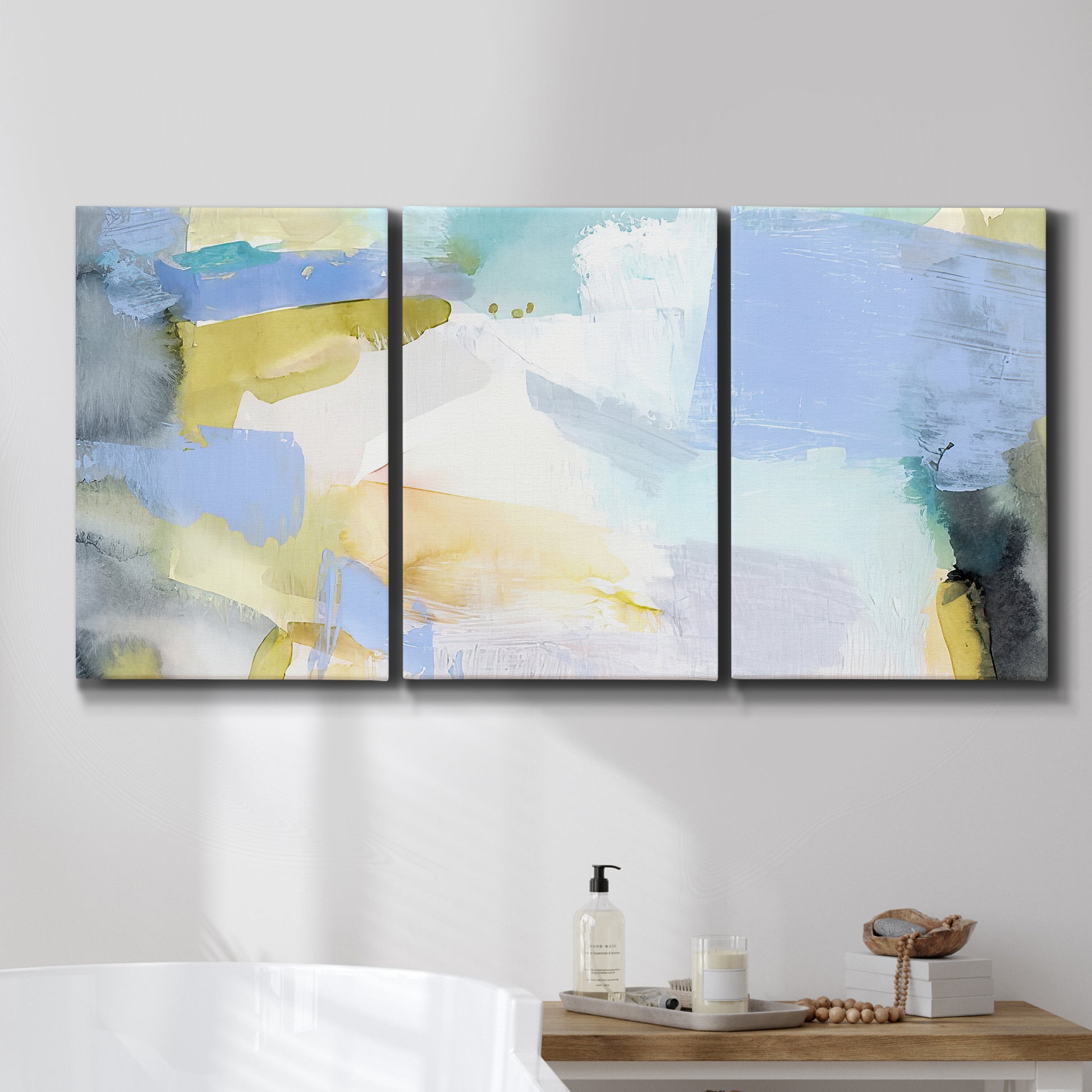 Three-panel canvas wall art featuring soft abstract spring watercolor tones, displayed in a bathroom above a bathtub.