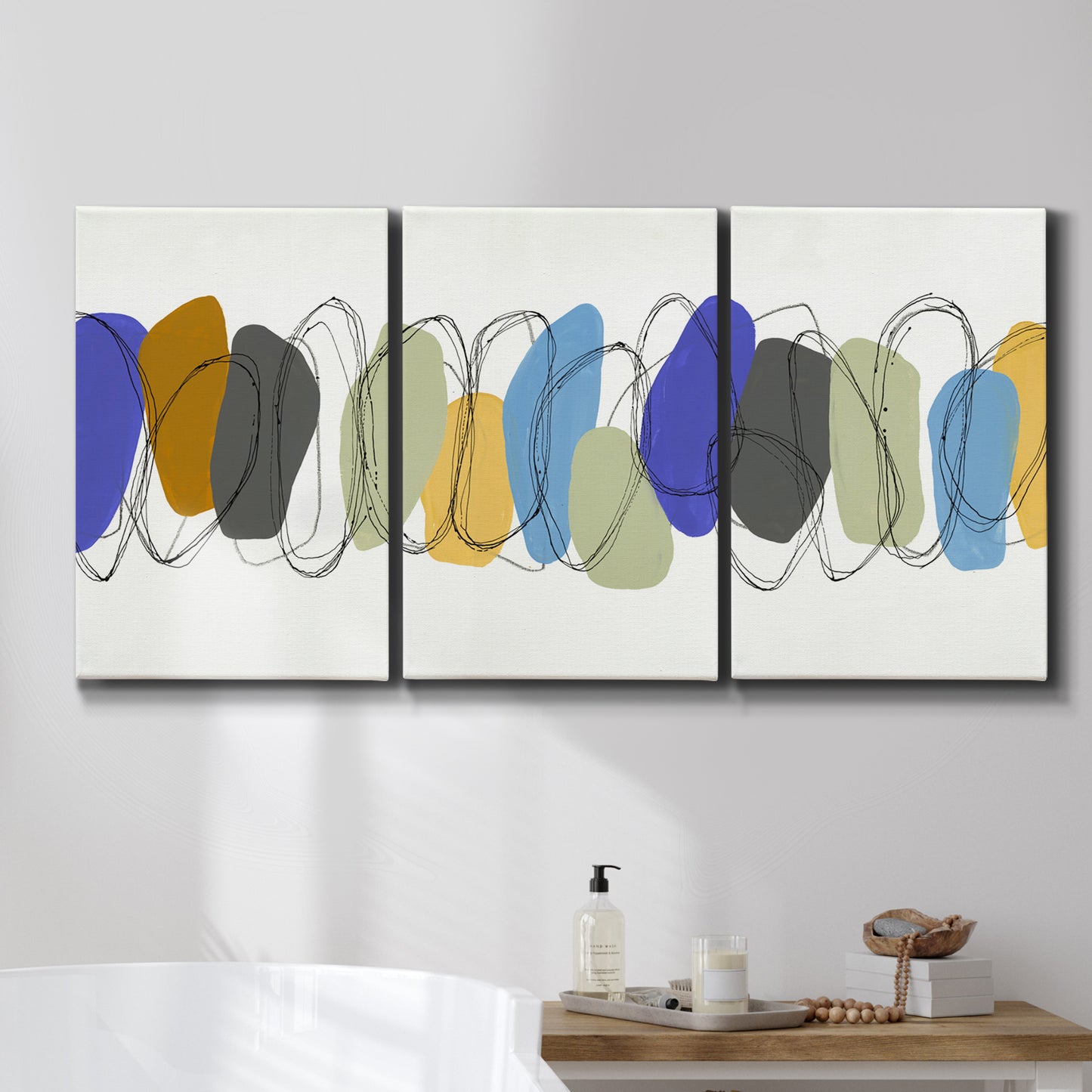 Three-panel canvas wall art featuring minimalist geometric abstract spacing, displayed in a bathroom above a bathtub.
