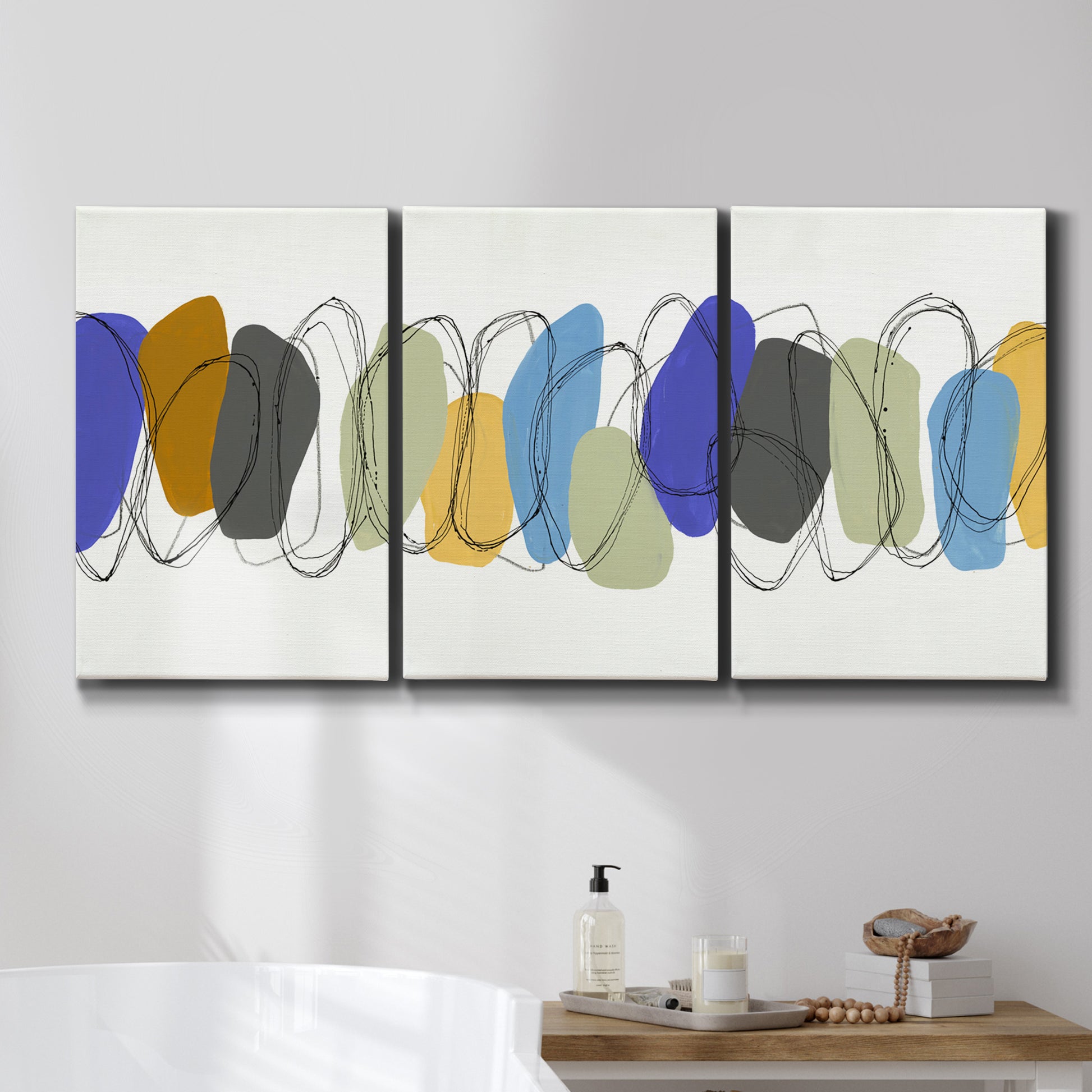 Three-panel canvas wall art featuring minimalist geometric abstract spacing, displayed in a bathroom above a bathtub.
