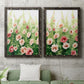 Set of two black barnwood framed canvas prints depicting a coordinated art pair of a field of pink coral and white flowers rendered as luminous impressionistic floral paintings above a sofa in a modern living room.