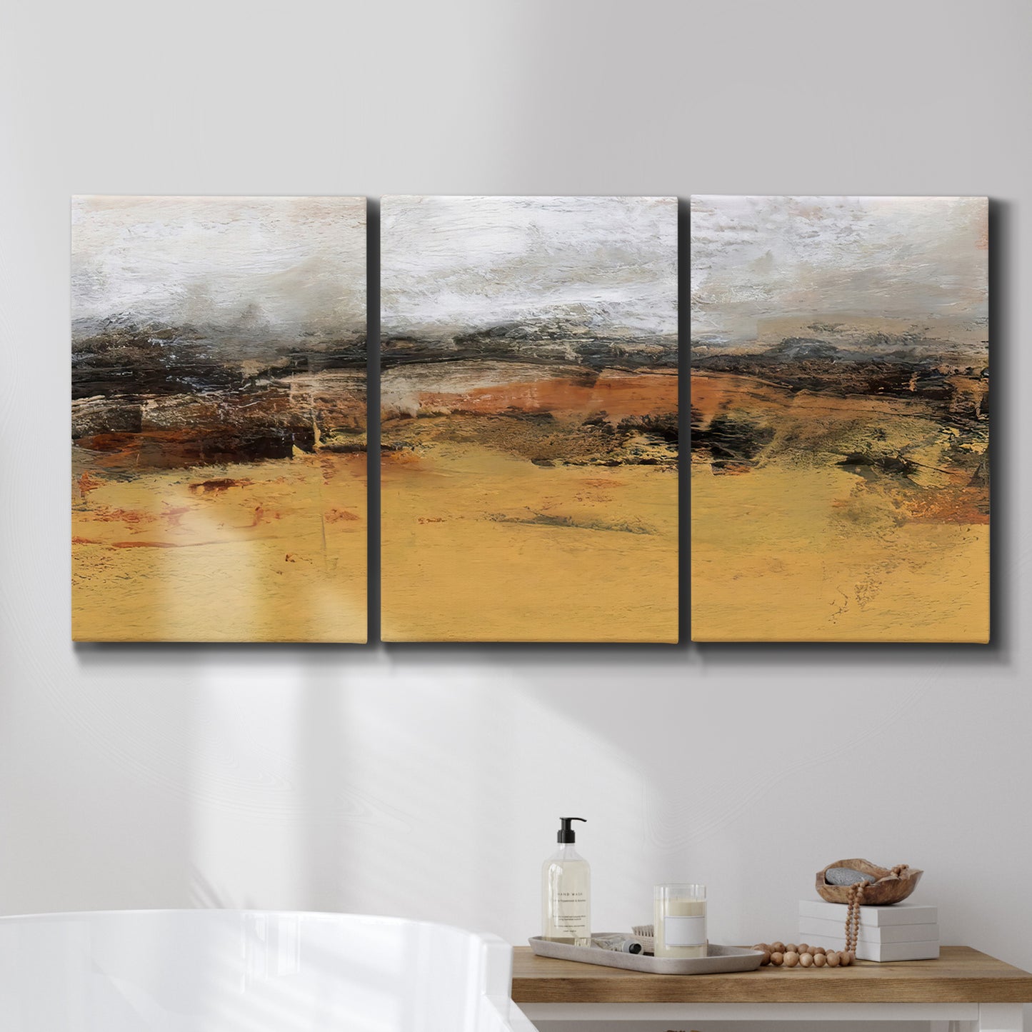 Three-panel canvas wall art featuring abstract bridge landscape in ochre, displayed in a bathroom above a bathtub.