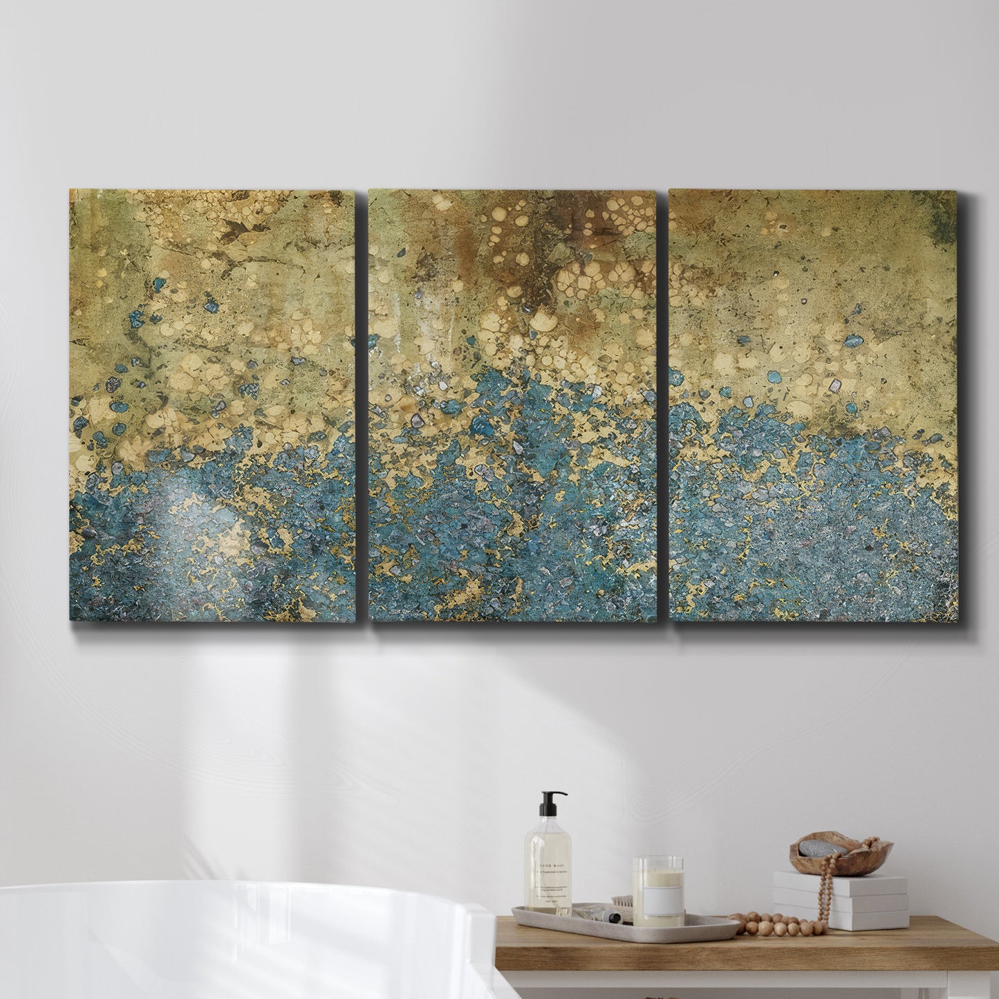 Three-panel canvas wall art featuring metallic abstract gold tones, displayed in a bathroom above a bathtub.