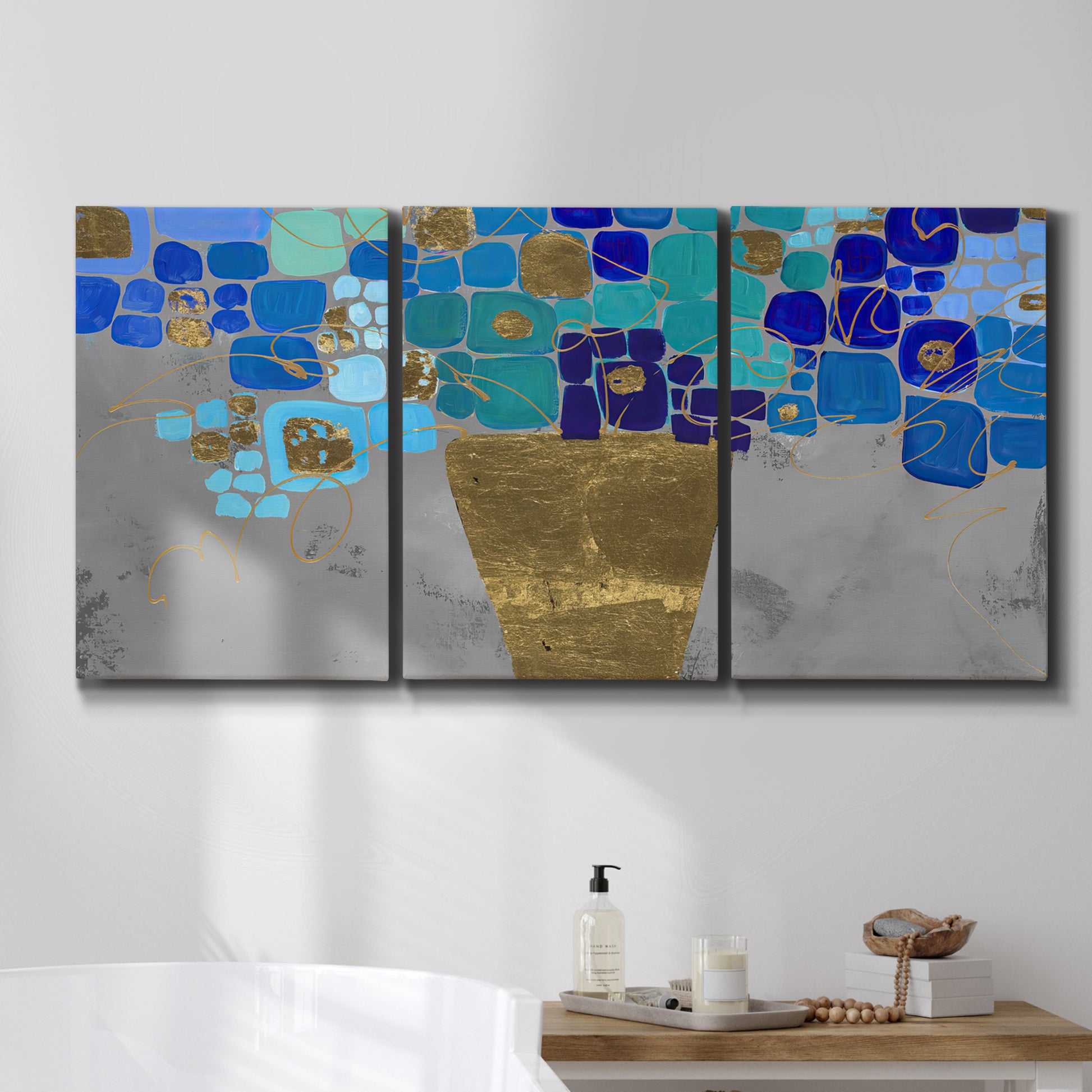 Three-panel canvas wall art featuring blue floral abstract botanical expression, displayed in a bathroom above a bathtub.