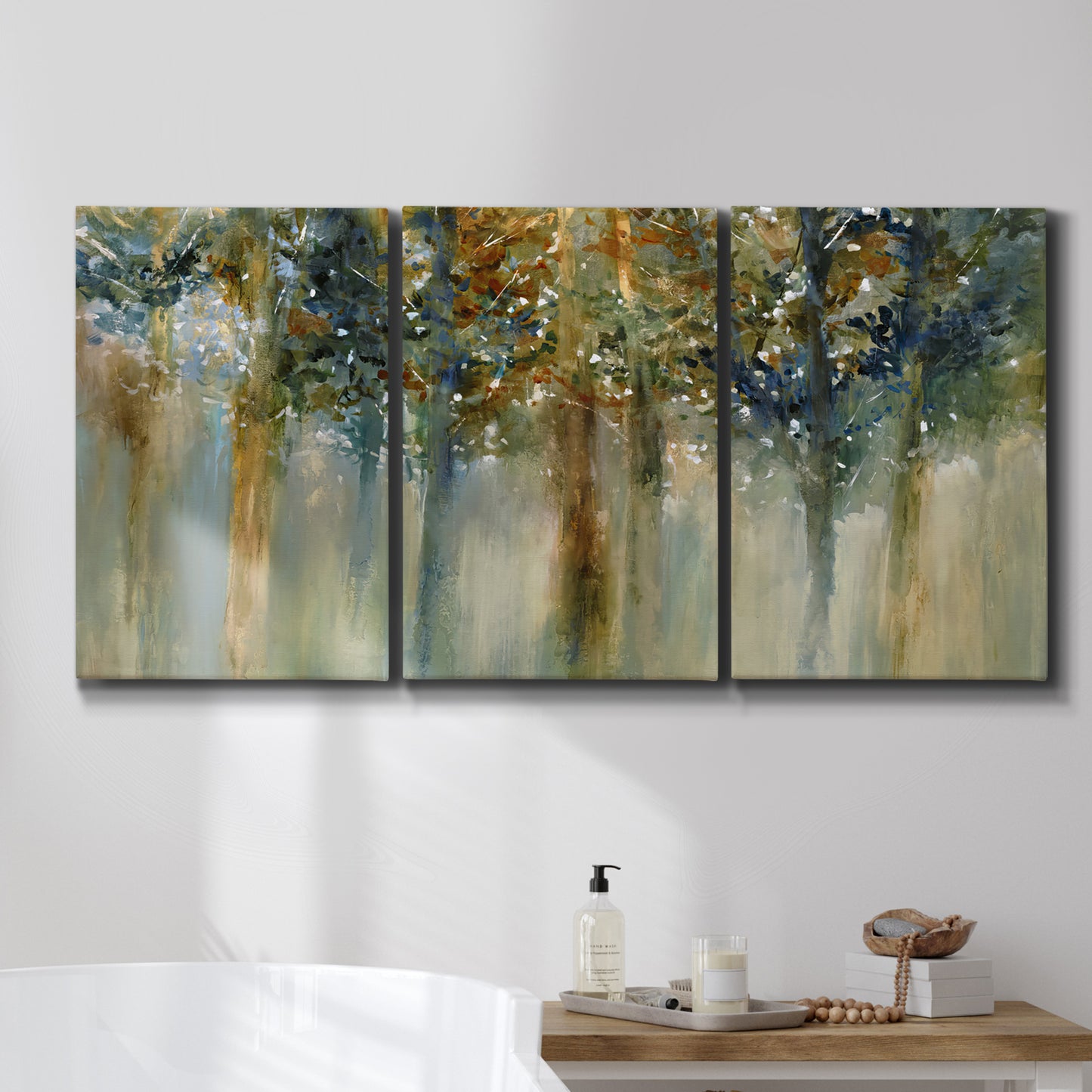 Three-panel canvas wall art featuring earth toned abstract leaf textures, displayed in a bathroom above a bathtub.