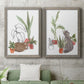 Set of two gray barnwood framed canvas prints depicting a coordinated art pair of cats tucked among collections of potted houseplants rendered as whimsical botanical animal illustrations above a sofa in a modern living room.