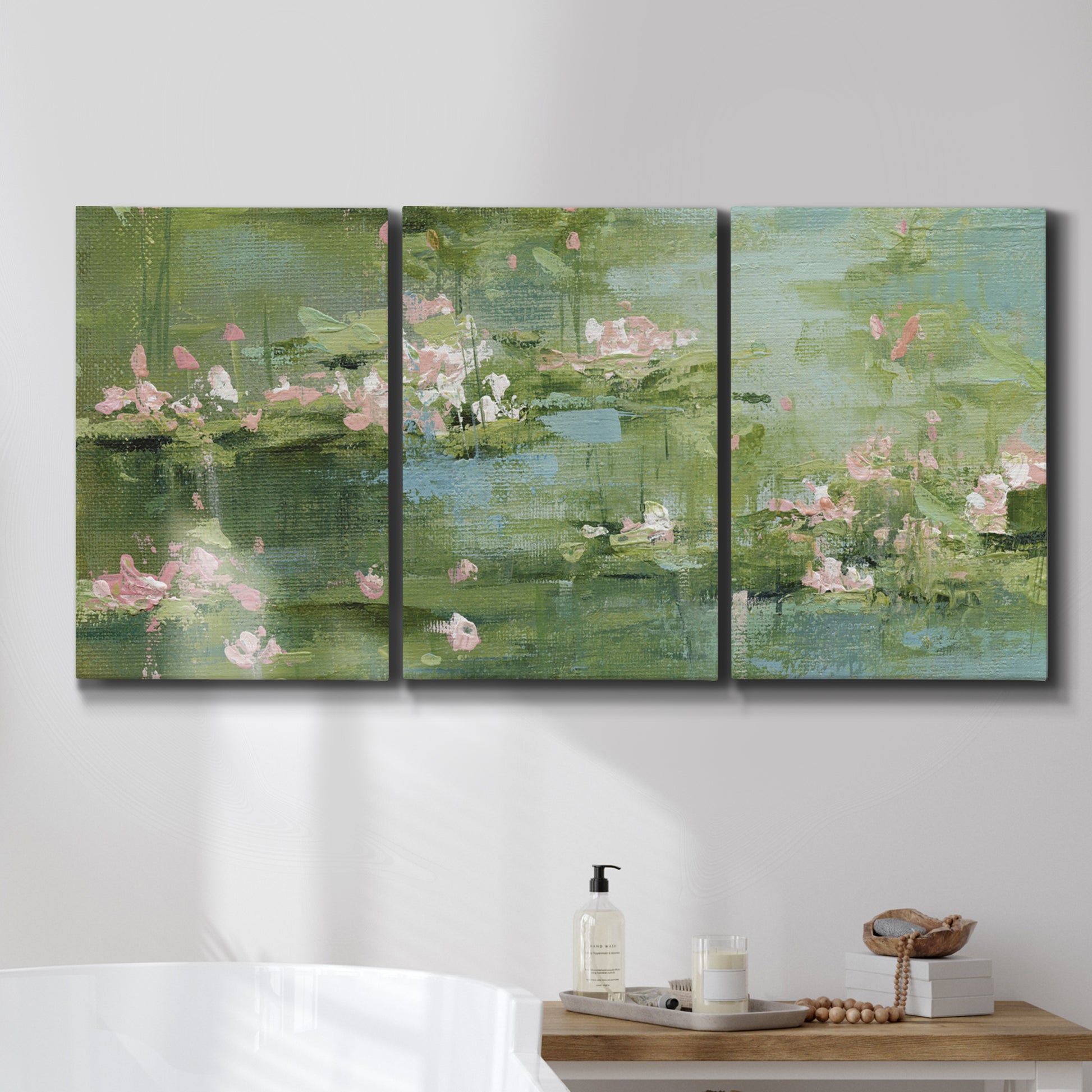 Three-panel canvas wall art featuring soft green water lilies, displayed in a bathroom above a bathtub.