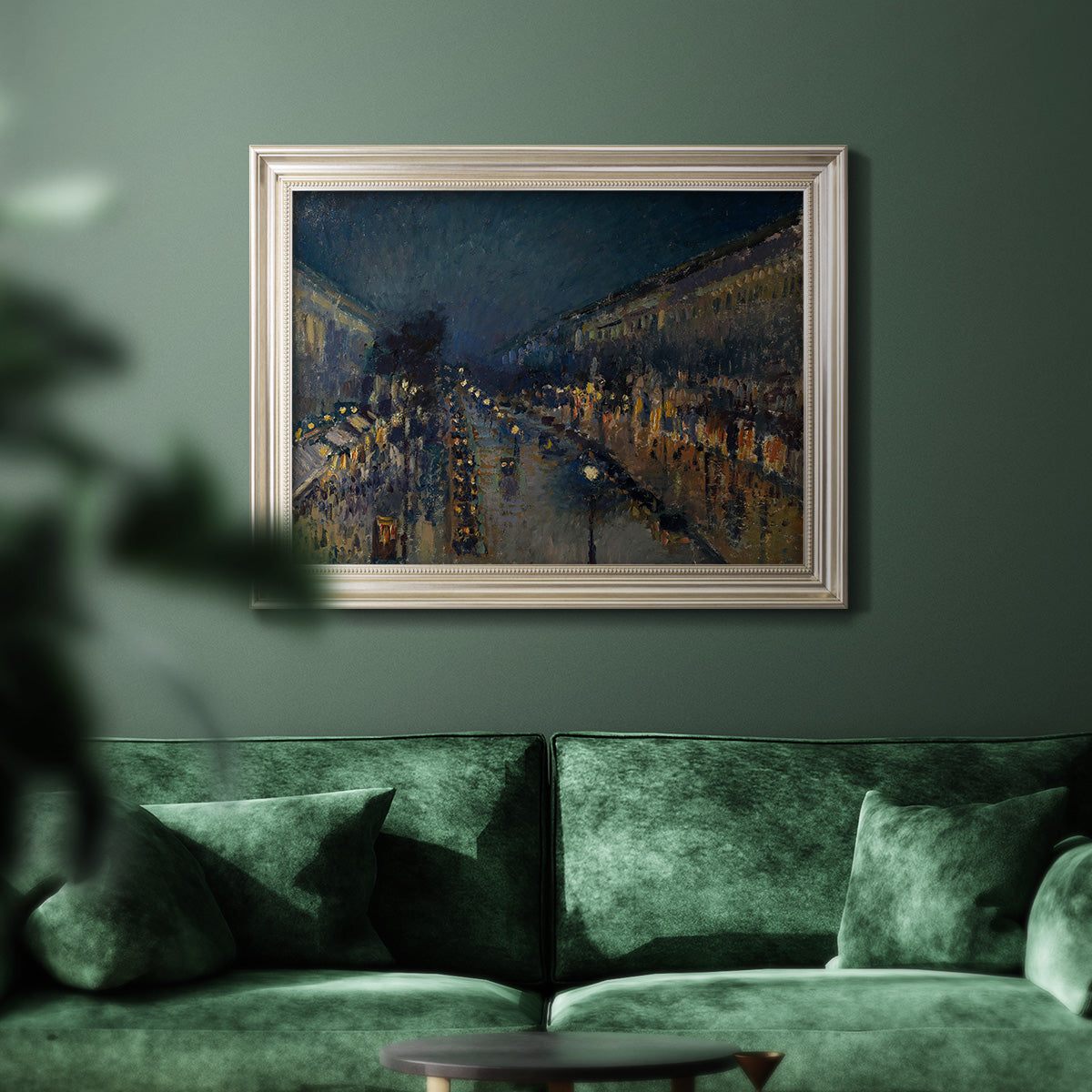 Impressionist nighttime Paris street scene by Camille Pissarro in an ornate champagne frame displayed in a dark-toned interior setting.