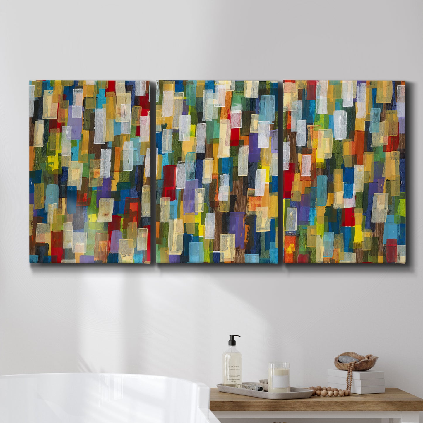 Three-panel canvas wall art featuring colorful confetti style abstraction, displayed in a bathroom above a bathtub.
